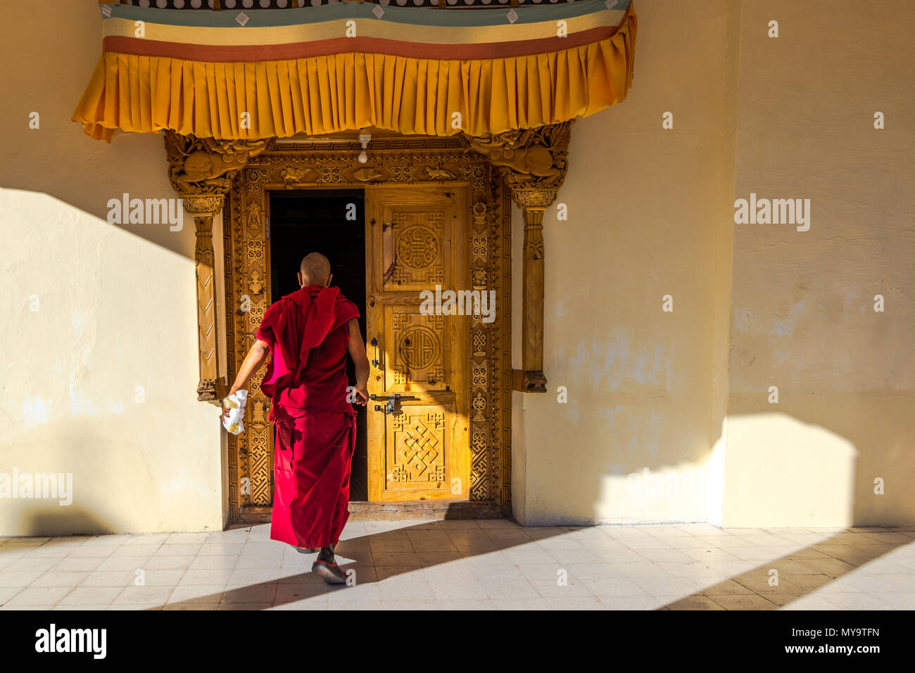 Tibetischer Mönch betritt das Gebäude durch eine reich geschnitzte Tür.Indien Ladakh 2015 Stockfoto