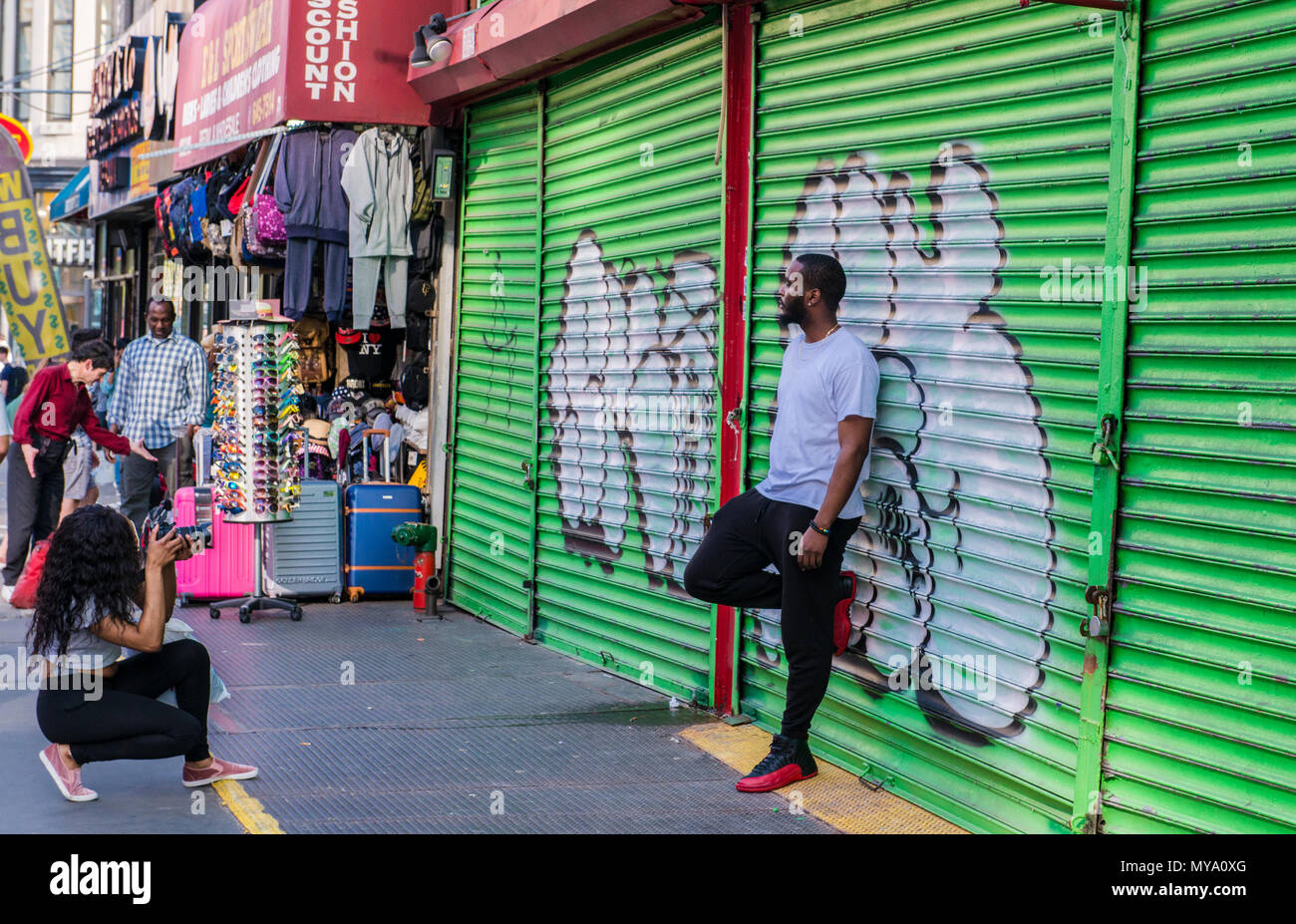 Mann gegen Graffiti bedeckt Metall Verschluss schiefen, posiert für die Fotografen, New York City, USA Stockfoto