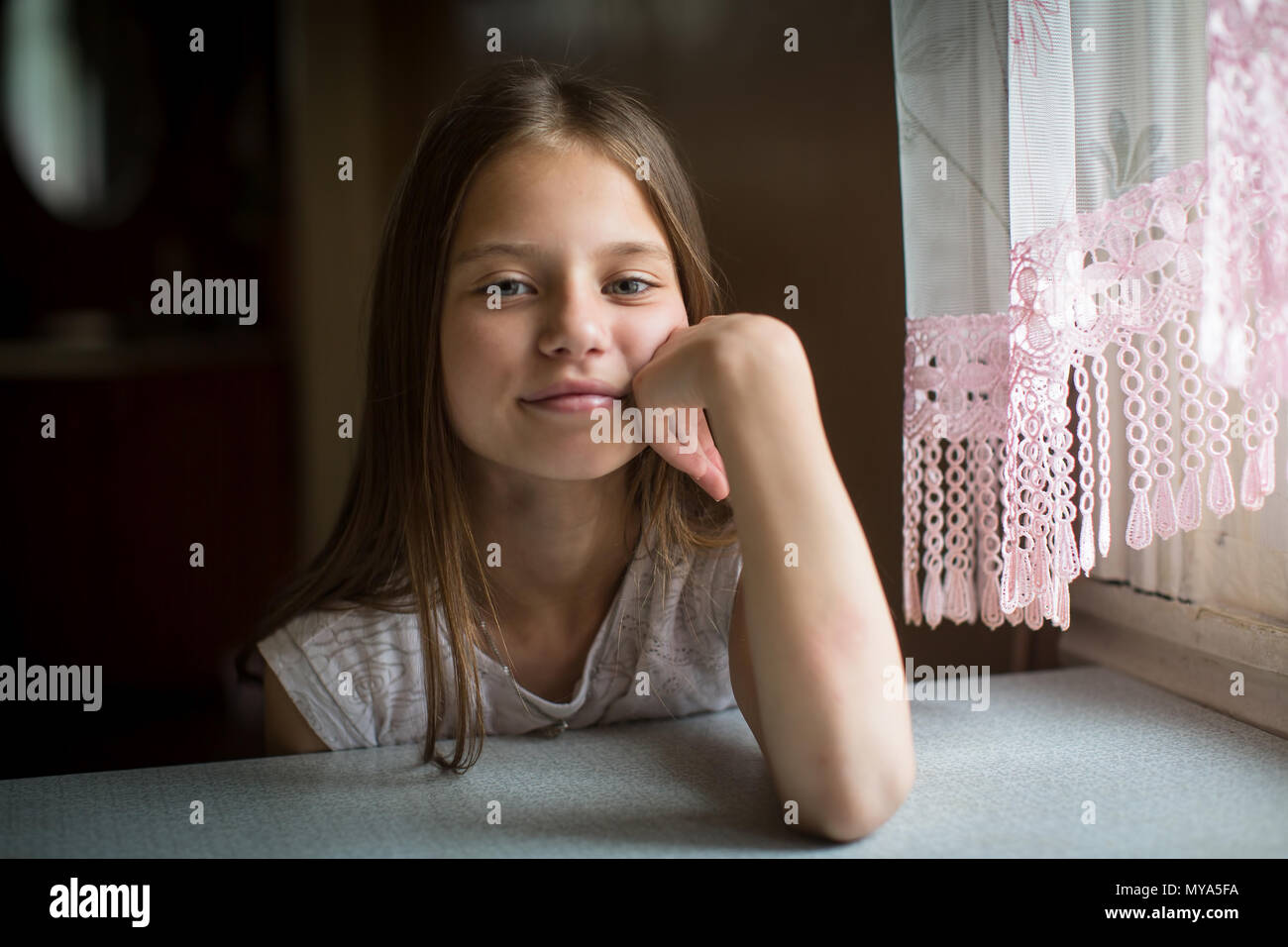 Portrait von Süße 10-jährige Mädchen am Tisch sitzen. Stockfoto