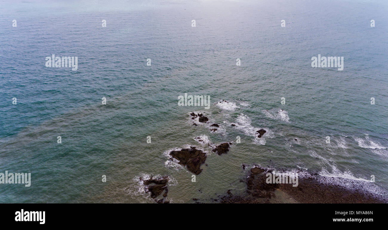 Erstaunlich, felsigen Strand Ufer. Bild von braunen und schwarzen Felsen durch blaue Wasser umgeben. Stockfoto