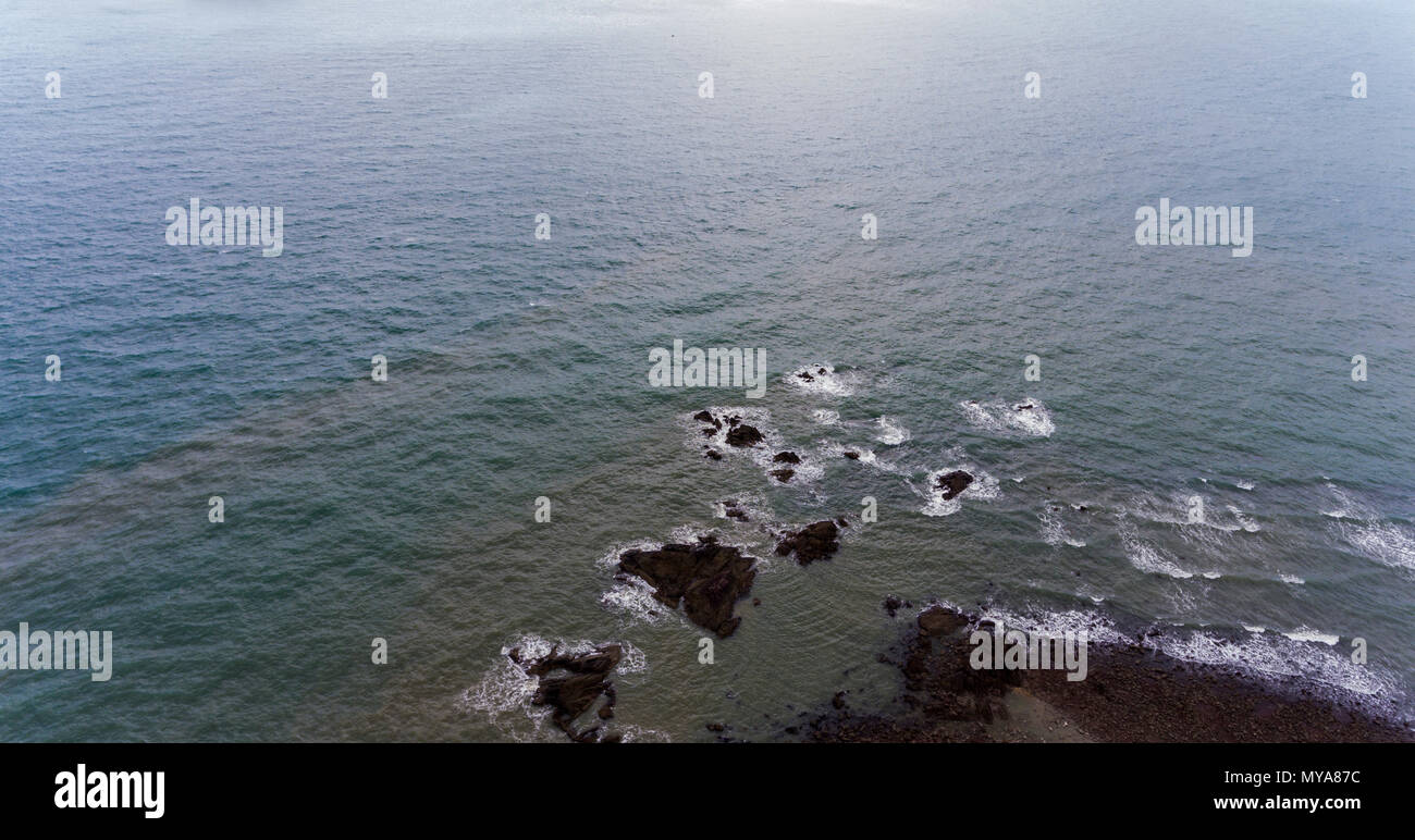 Erstaunlich, felsigen Strand Ufer. Bild von braunen und schwarzen Felsen durch blaue Wasser umgeben. Stockfoto
