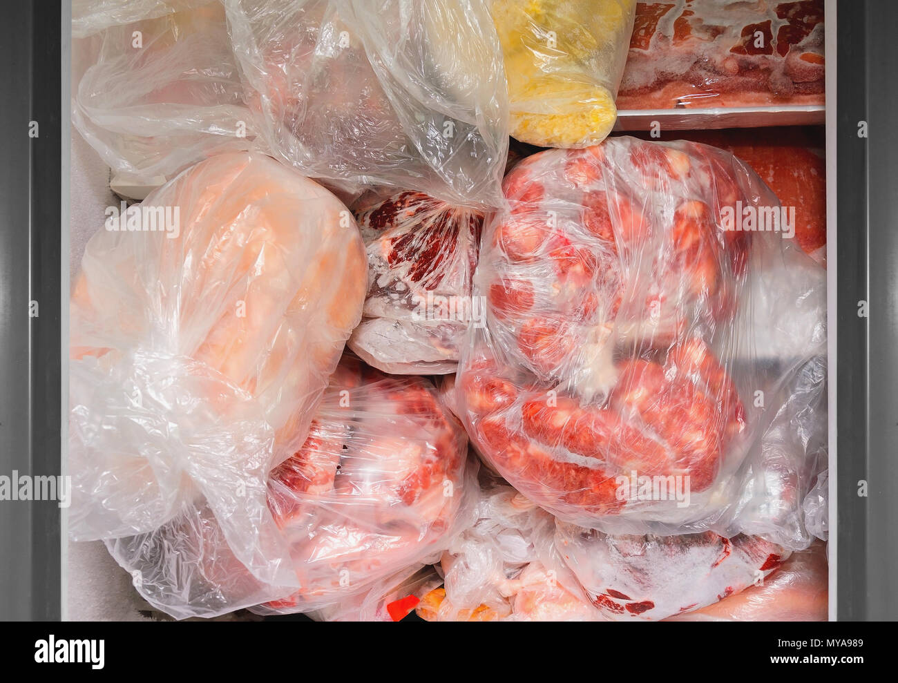 Gefrorene Lebensmittel im Gefrierschrank. Tüten gefroren Fleisch in einer horizontalen Gefrierschrank. Die Konservierung von Lebensmitteln. Stockfoto