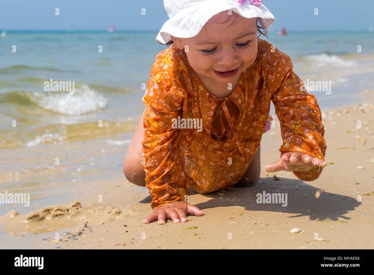 Hübsches kleines Mädchen kriechen auf den Strand, das fröhliche Kind, die Emotionen eines Kindes Stockfoto
