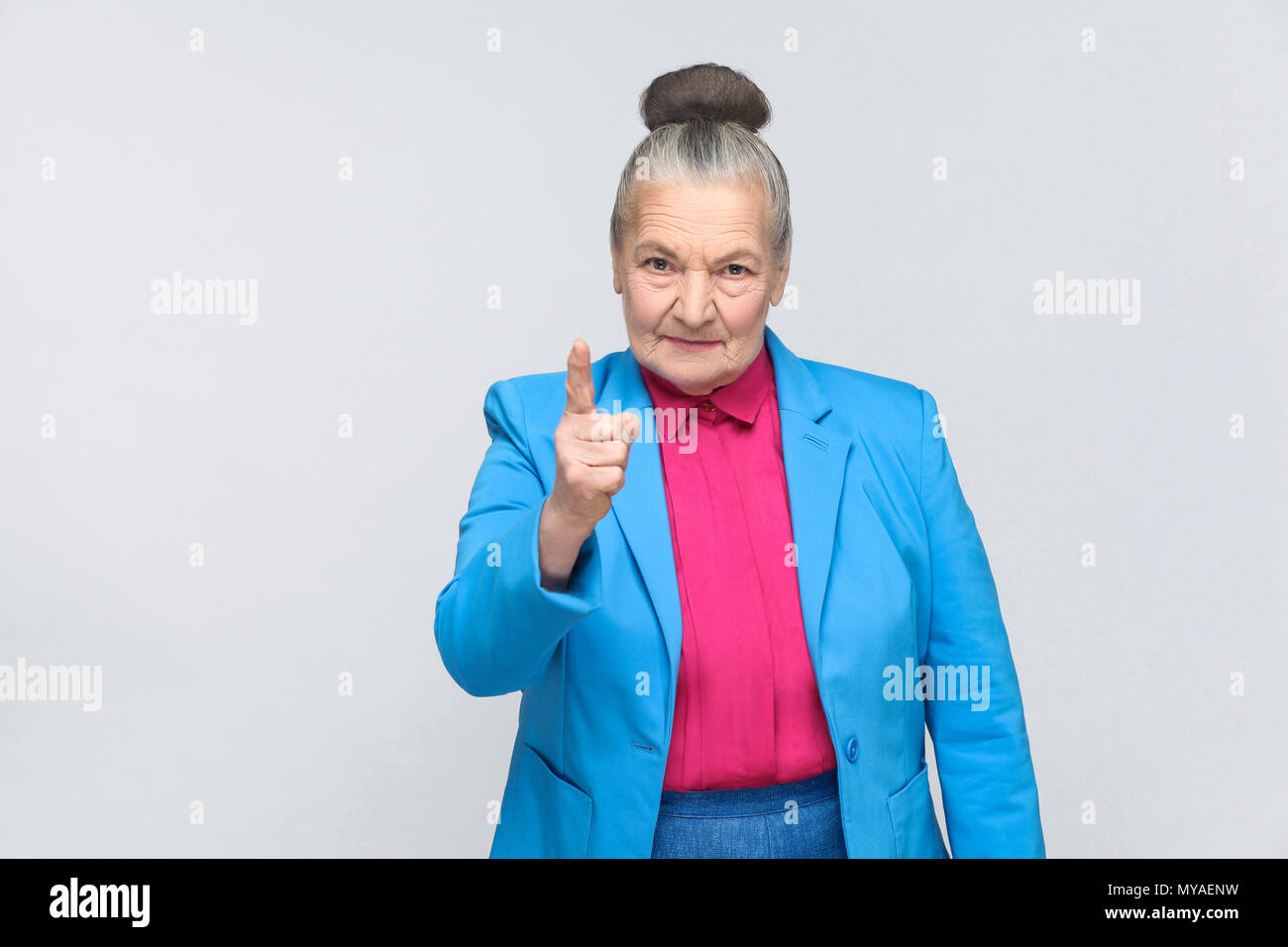 Wütend gealterte Frau Sie Warnung. Emotionen und Gefühle. emotionale Ausdruckskraft Großmutter mit Hellblau und Rosa shirt stehend mit erhobenen Bun g Stockfoto