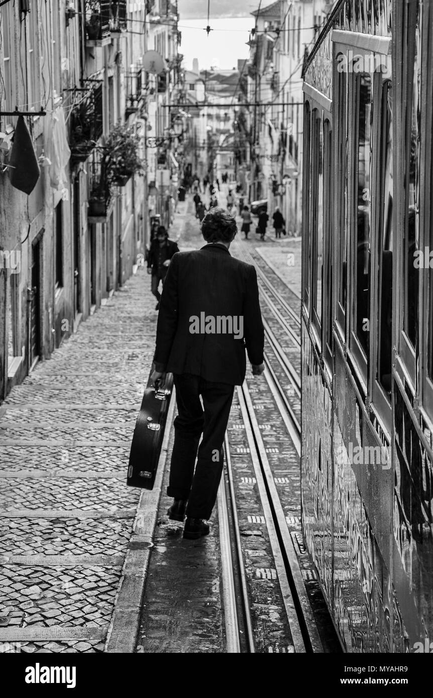 Lissabon, Portugal - Januar 23, 2010: Stree Szene in der Stadt Lissabon mit einem Mann, der einen Gitarre zu Fuß die Bica Straße. Stockfoto