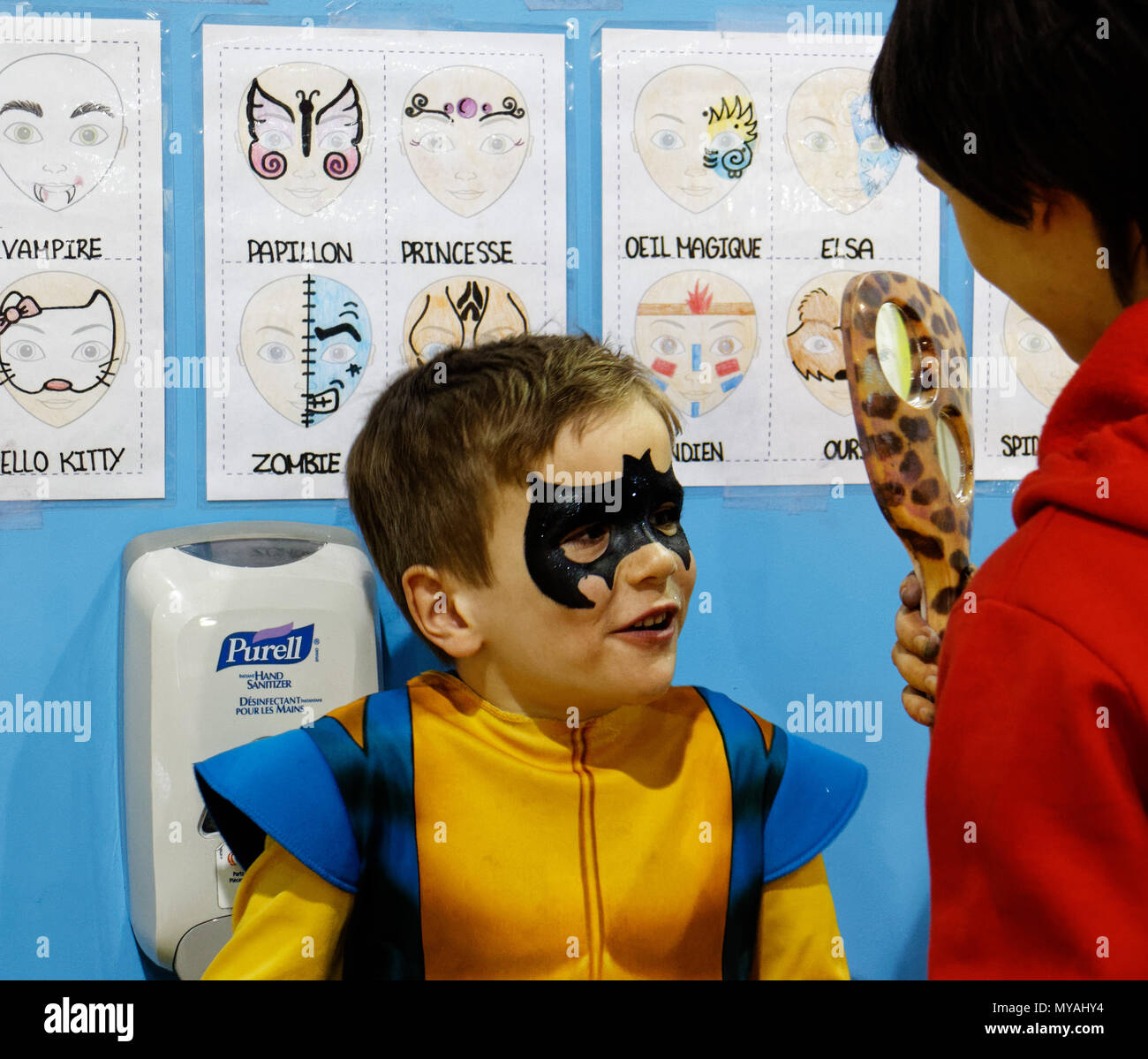 Ein Junge (6 Jahre alt) bewundern seine neue Batman Gesicht Farbe im Spiegel Stockfoto