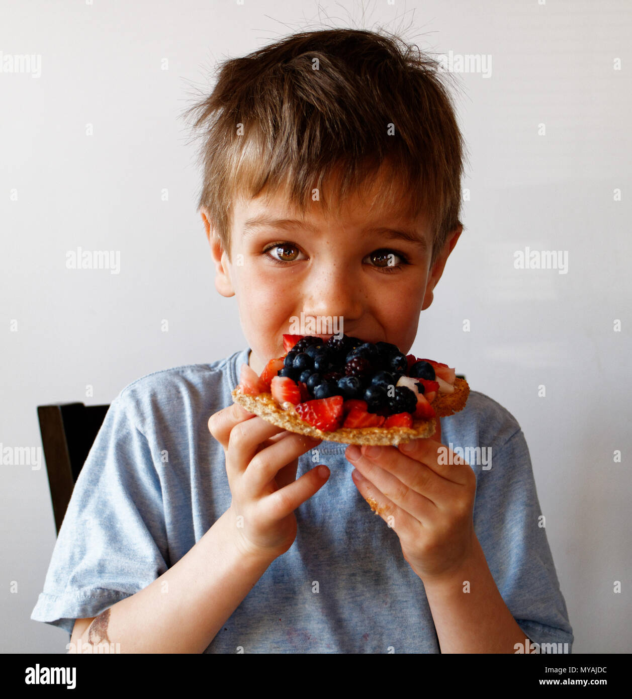 Ein Portrait eines Jungen (6 Jahre alt) eine gesunde Frühstück mit Obst und Toast. Stockfoto