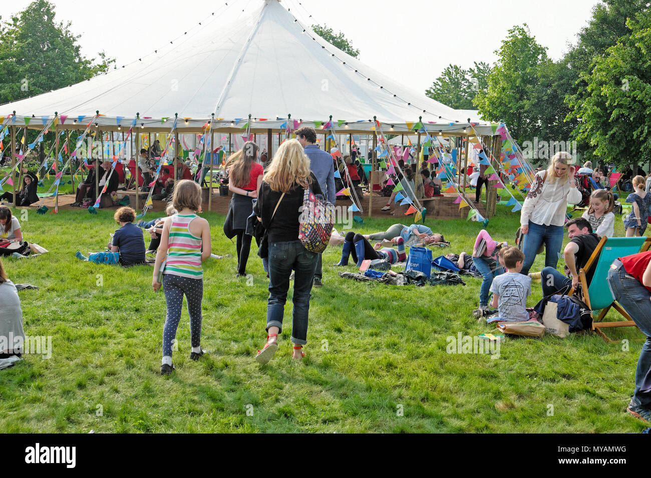 Menschen entspannten Sitzen und Liegen auf dem Boden lesen außerhalb von Festzelt auf dem Hay Festival Website in Sunshine 2018 Hay-on-Wye Wales UK KATHY DEWITT Stockfoto