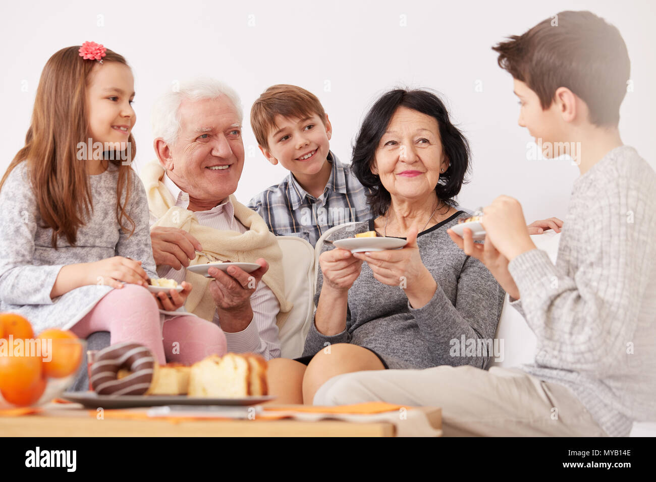 Glückliche Familie sitzt auf einem Sofa und einem Dessert Stockfoto