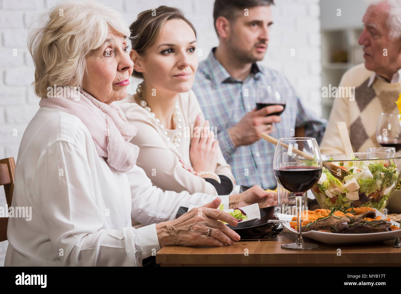 Zwei Frauen und zwei Männer sitzen am Tisch beim Abendessen mit der Familie, Reden Stockfoto