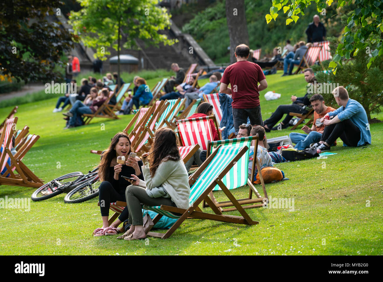 Menschen entspannend auf den Liegestühlen am Nachmittag Sonne in die Princes Street Gardens in Edinburgh, Schottland, Großbritannien Stockfoto