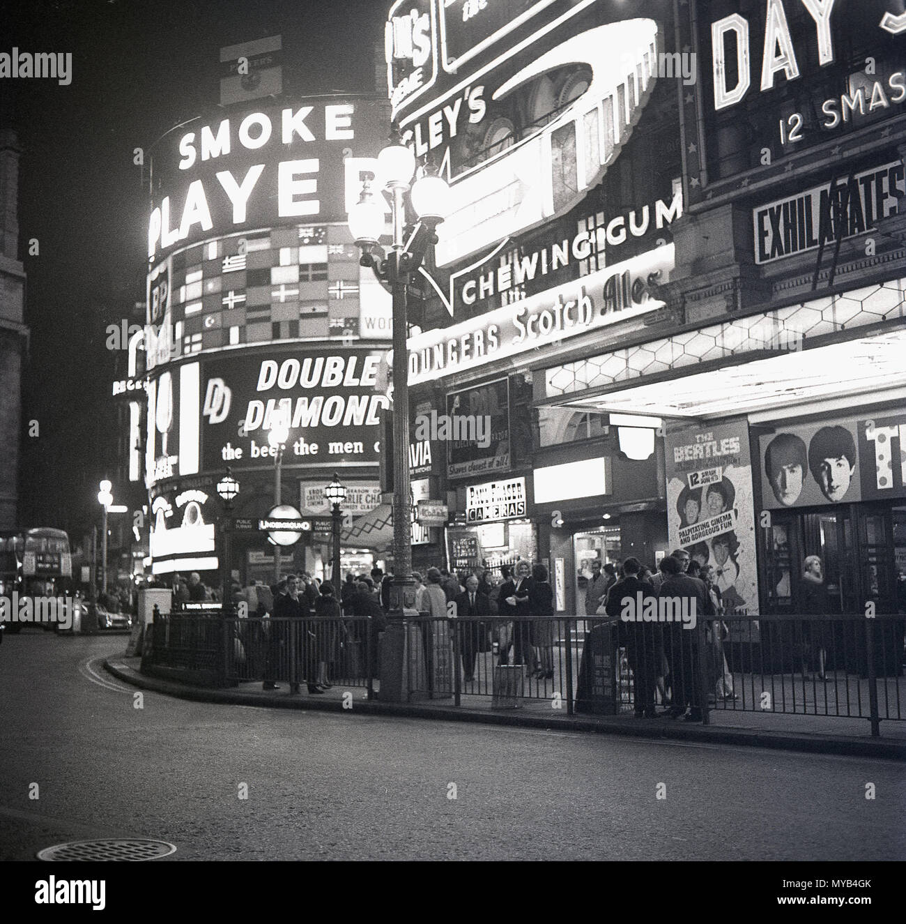 1964, historisches Bild, Menschen vor dem Pavilion Theatre am Piccadilly Circus, London, warten darauf, 'A Hard Day's Night' zu sehen, den Film mit der legendären britischen Popgruppe, den Beatles, während der Höhepunkt des Wahns von 'Beatlemania'. Die Band aus Liverpool, England, hat die Musik in dieser Zeit verändert und der Film war ein großer Erfolg. Der Straßenknoten und der öffentliche Raum wurden 1819 gebaut, um Piccadilly mit der Regent Street zu verbinden. Im West End der Stadt können einige der berühmten britischen Marken des Tages auf den Werbetafeln gesehen werden, einschließlich Spieler Zigaretten und Double Diamond Bier. Stockfoto