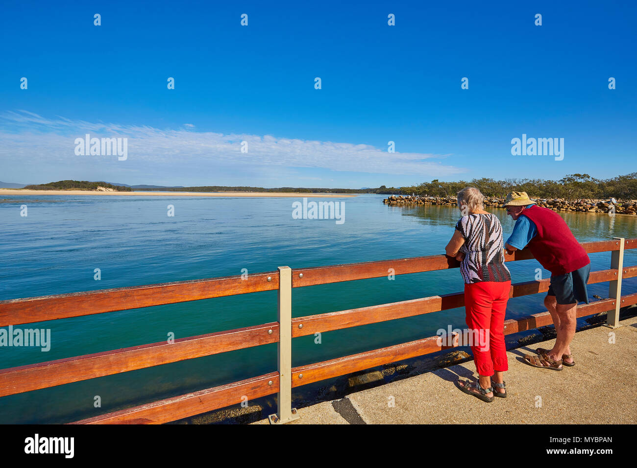 Ein Mann und eine Frau lehnte sich auf einen Zaun an der Kostenposition suchen, Nambucca Heads, New South Wales, Australien Stockfoto
