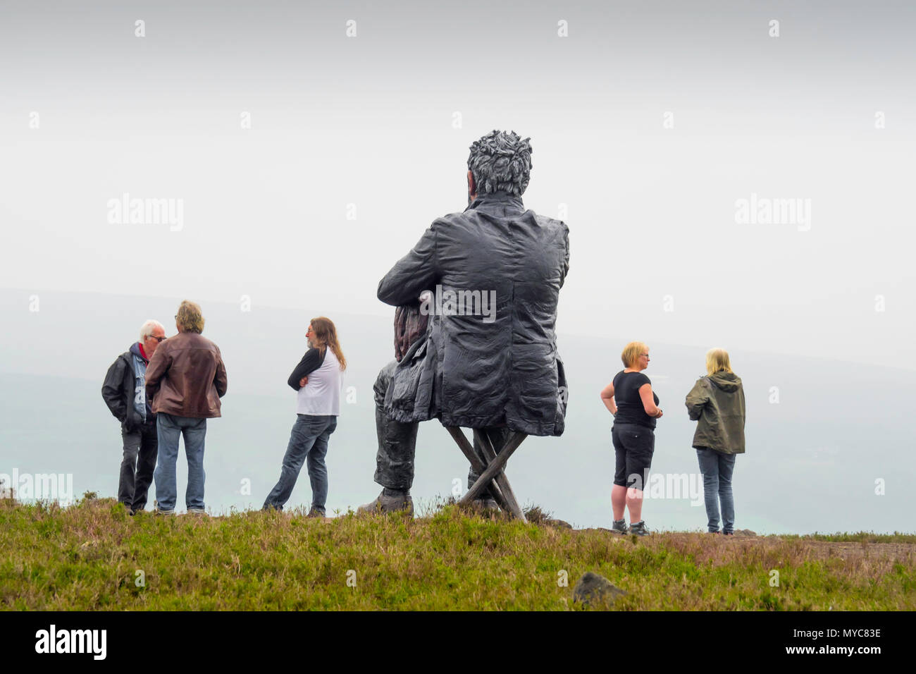 Wanderer plaudernd durch die sitzende Mann Skulptur des Künstlers Sean Henry auf Castleton in der North Yorkshire Moors National Park mit Blick auf die westerdale Stockfoto