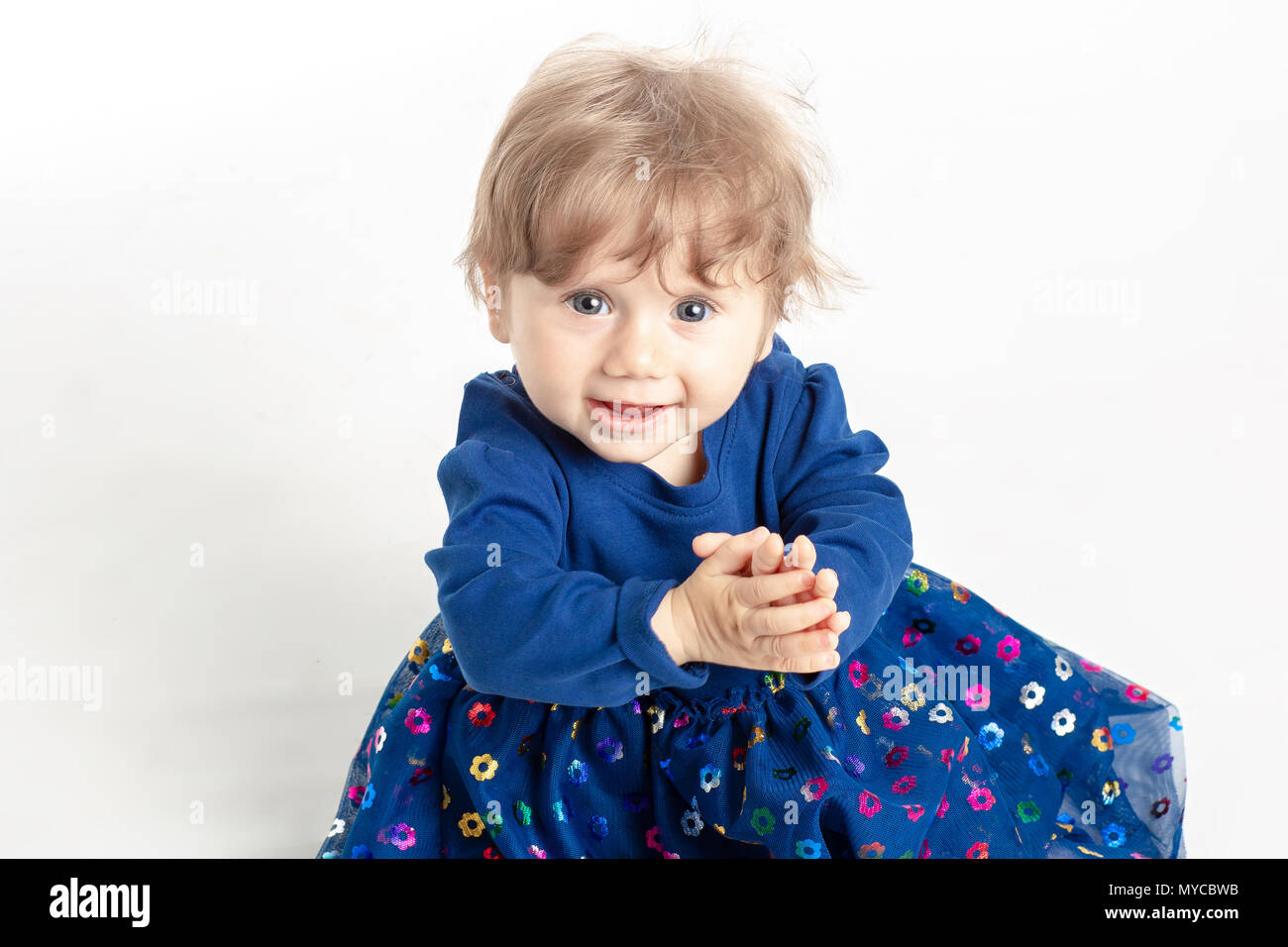 Portrait von Happy Baby Mädchen, 1 Jahr alt mit blauen Augen und Kleid in Studio posieren. Weißer Hintergrund. Konzept Das Glück. Stockfoto