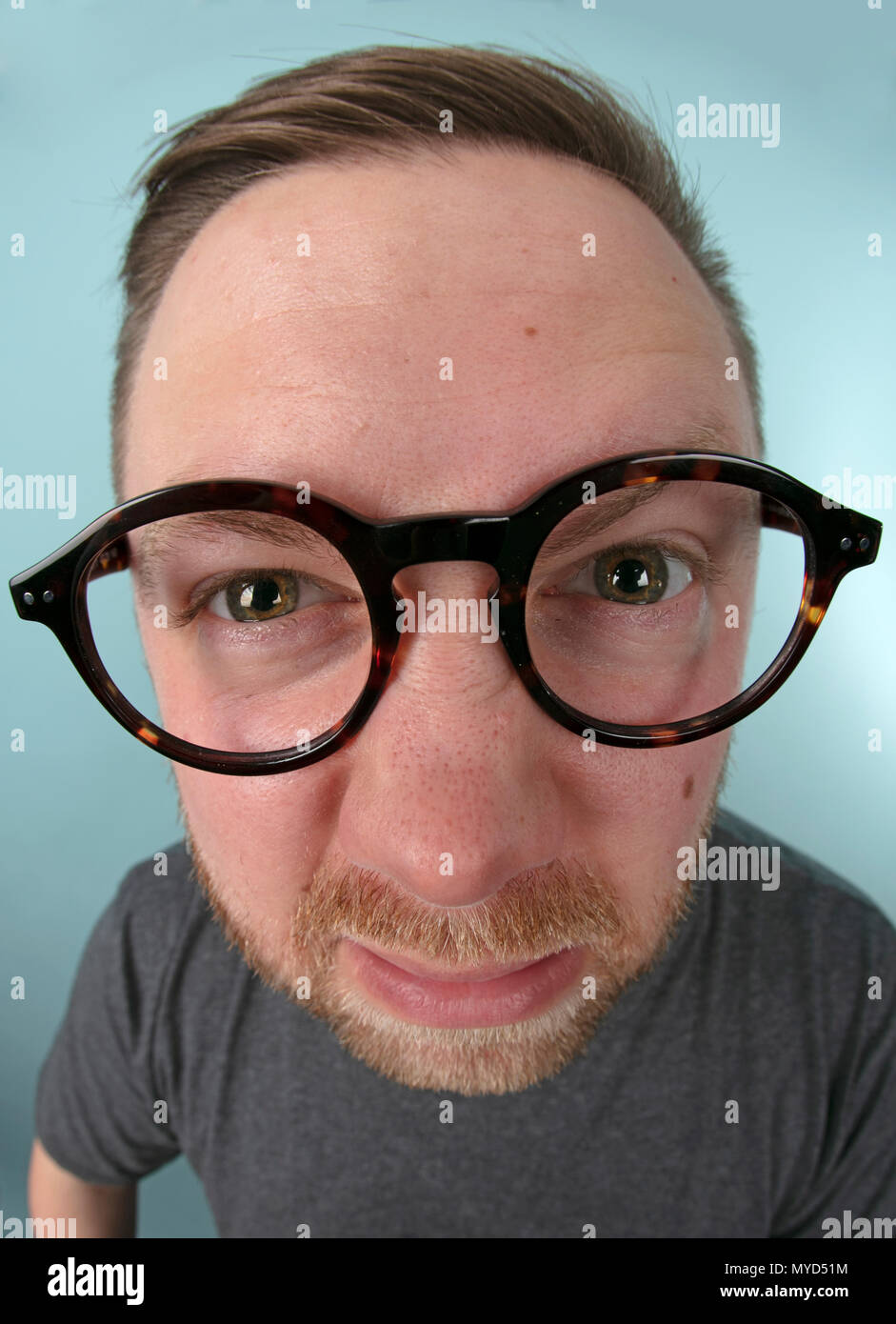 Mann mit großen Gläsern nach vorne Strecken in das Objektiv in einer  verzerrten Perspektive seine Augen und Brille betont in einem Spaß  portrait-to-Peer Stockfotografie - Alamy