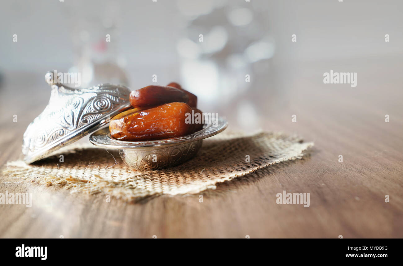 Frisches Obst Termine in einem silbernen metall Schüssel auf einem Stück Sack auf Nussbaum Holz Tisch Stockfoto