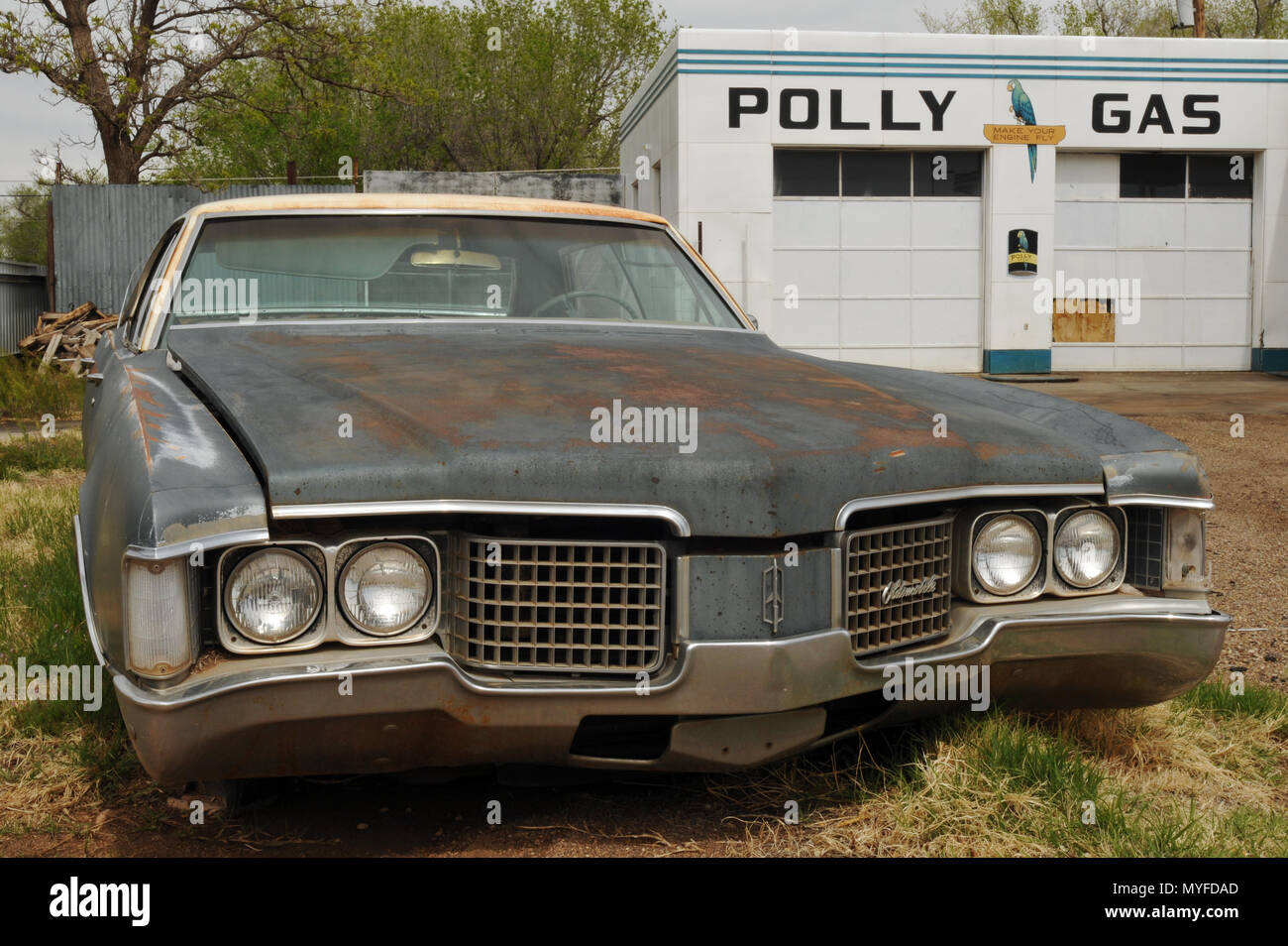 Ein rosten Oldsmobile sitzt vor einer ehemaligen Garage mit einer Polly Gas Zeichen und Logos, die in der Route 66 Stadt Santa Fe, New Mexico gemalt. Stockfoto
