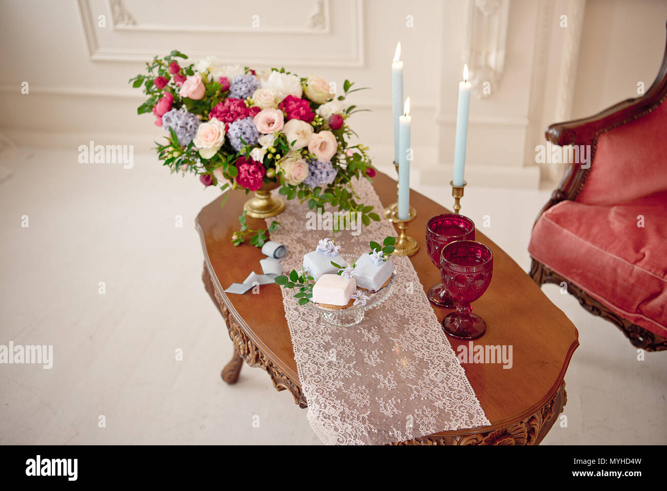 Dekoriert vintage Tabelle in weißen barocken Interieur mit roten Luxus Sofa. Tabelle ist für romantische Ereignis eingestellt. Stockfoto