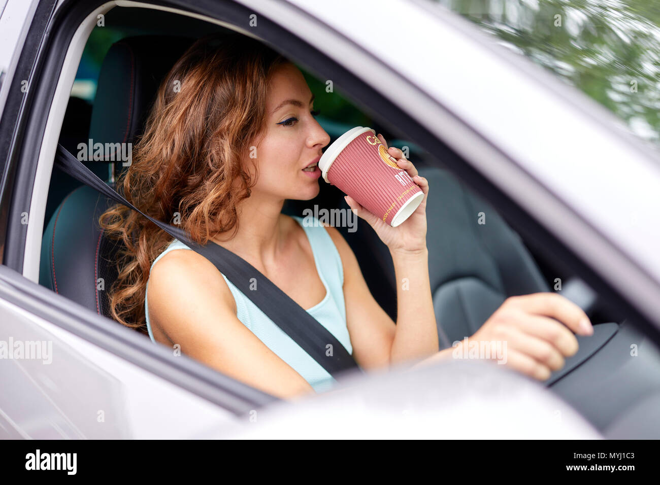 Frau trinkt Kaffee während der Fahrt Stockfoto