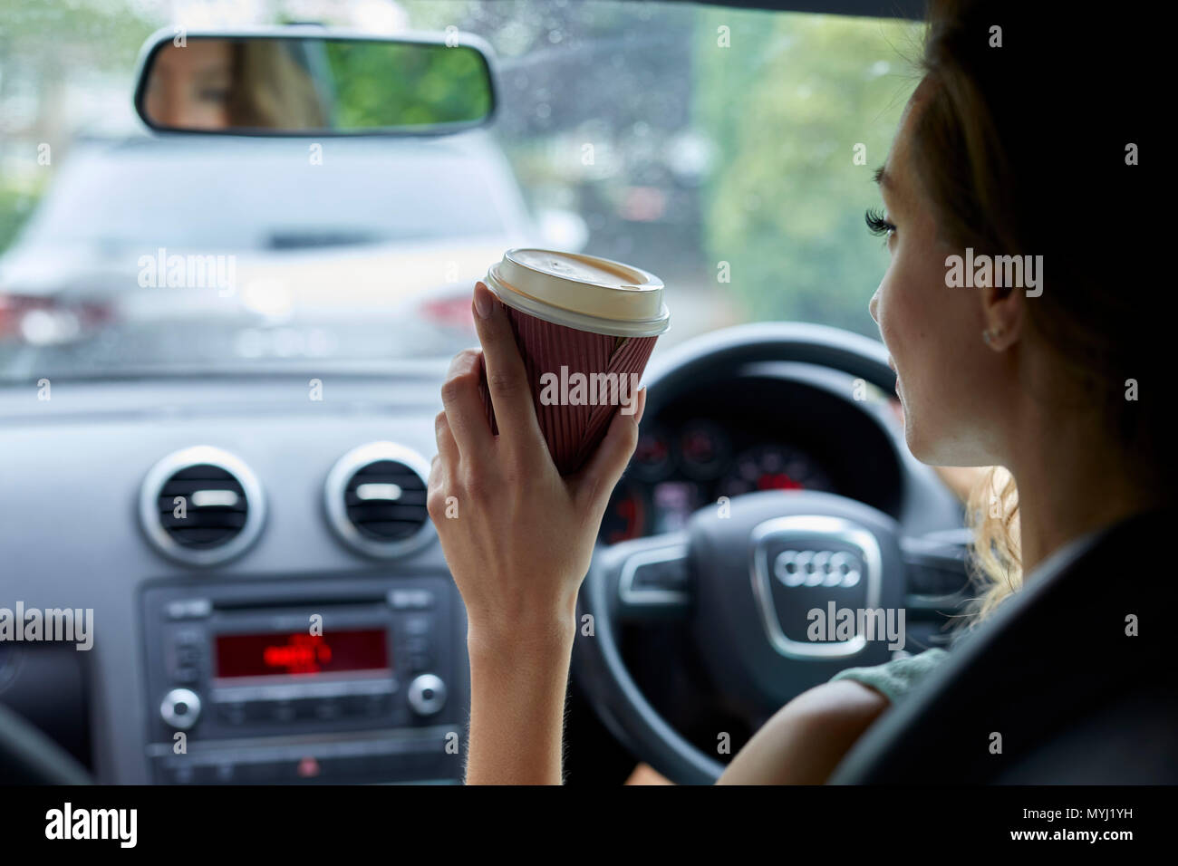 Frau trinkt Kaffee während der Fahrt Stockfoto
