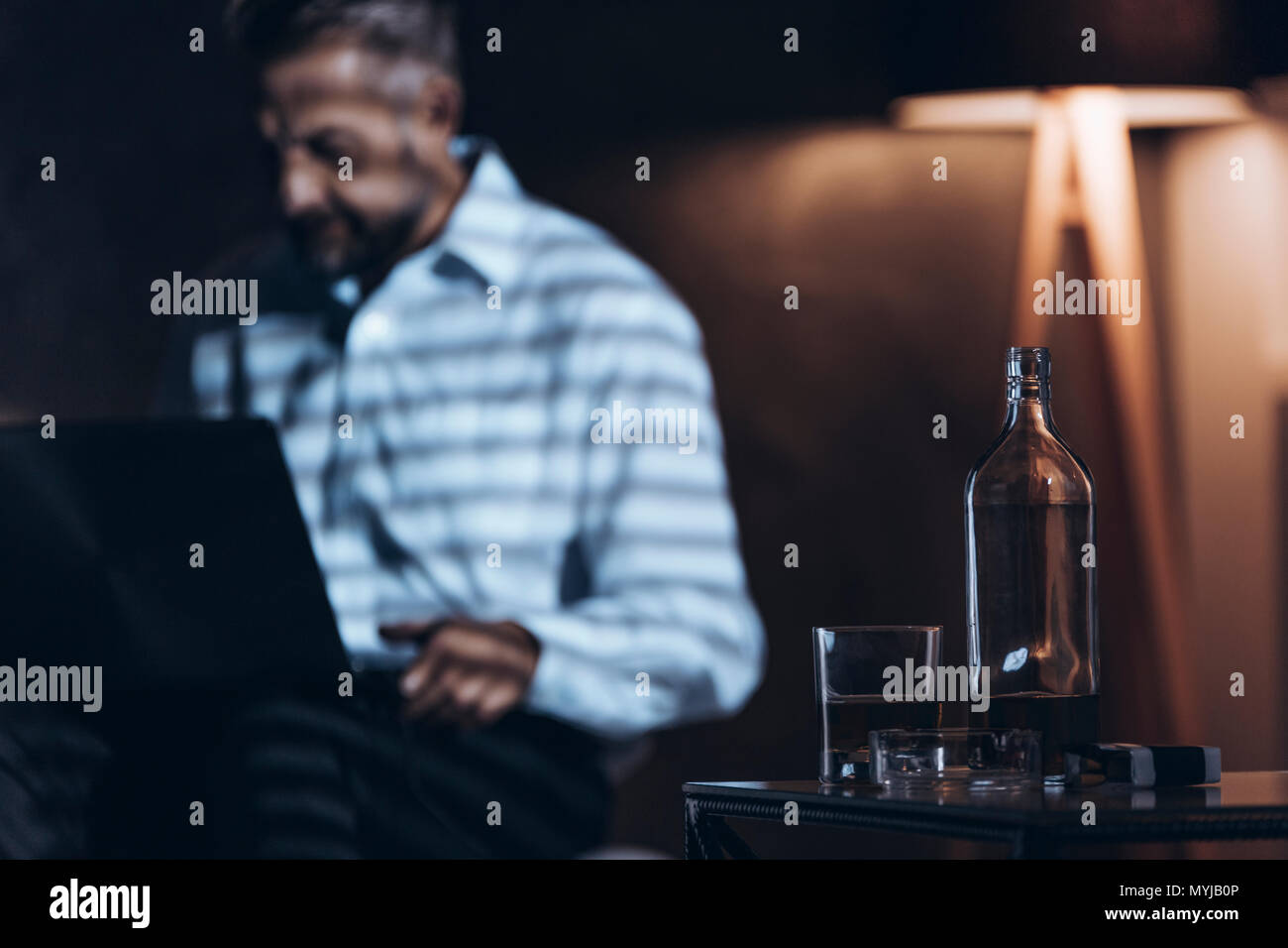 In der Nähe von Glas Flasche mit Alkohol. Workaholic mit Alkohol Problem Stockfoto