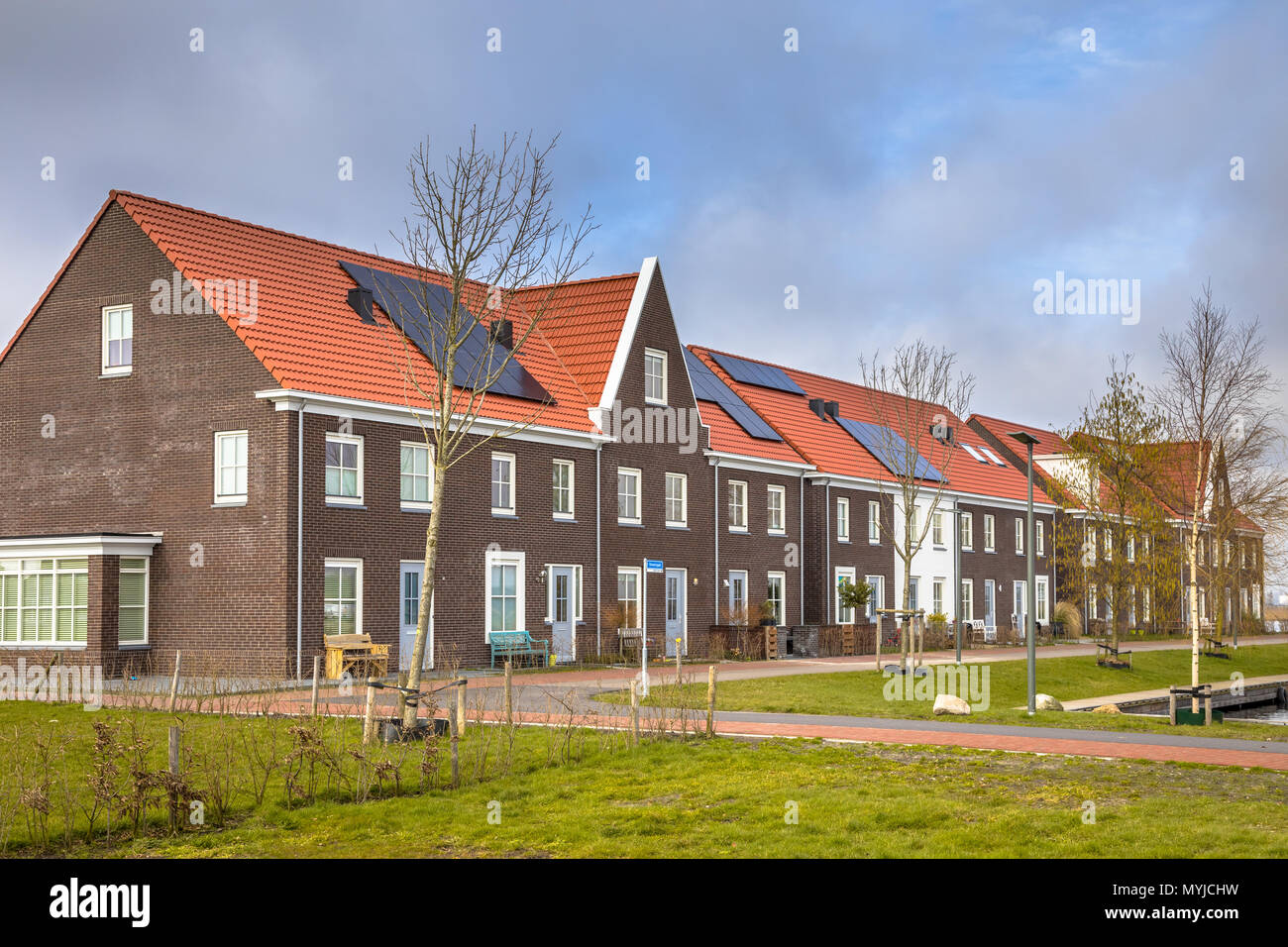 Moderne Reihenhäuser mit Solarzellen, braunen Backsteinen und roten Dachziegeln in Groningen Niederlande Stockfoto