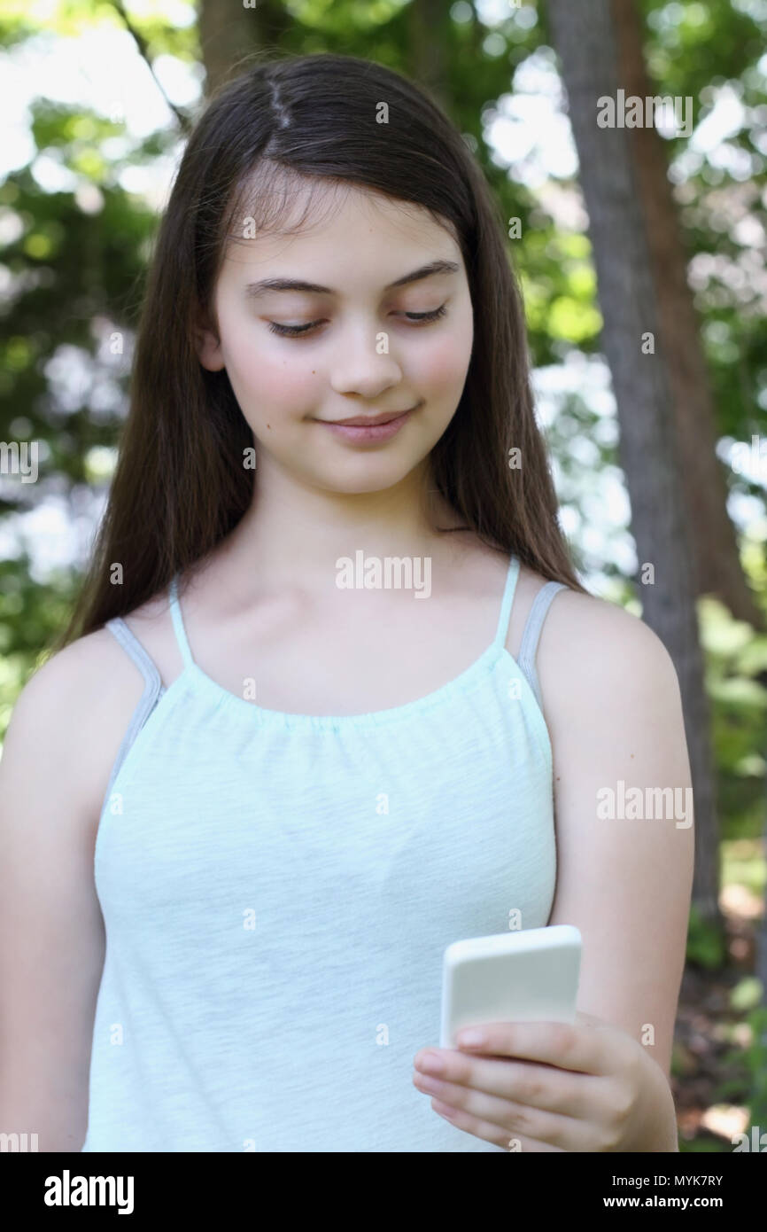 Glücklich lächelnde junge jugendmädchen beim Lesen einer SMS-Nachricht auf einem Smartphone. Selektiver Fokus auf jugendlich. Stockfoto