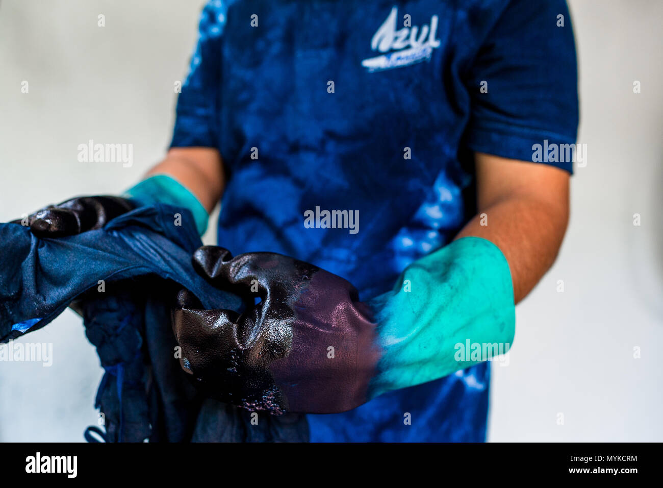 Eine Salvadorianische textile Dyer gilt ein natürlicher Farbstoff Indigo auf ein Tuch gewickelt in einem Handwerklichen Kleidung Workshop in Santiago Nonualco, El Salvador. Stockfoto