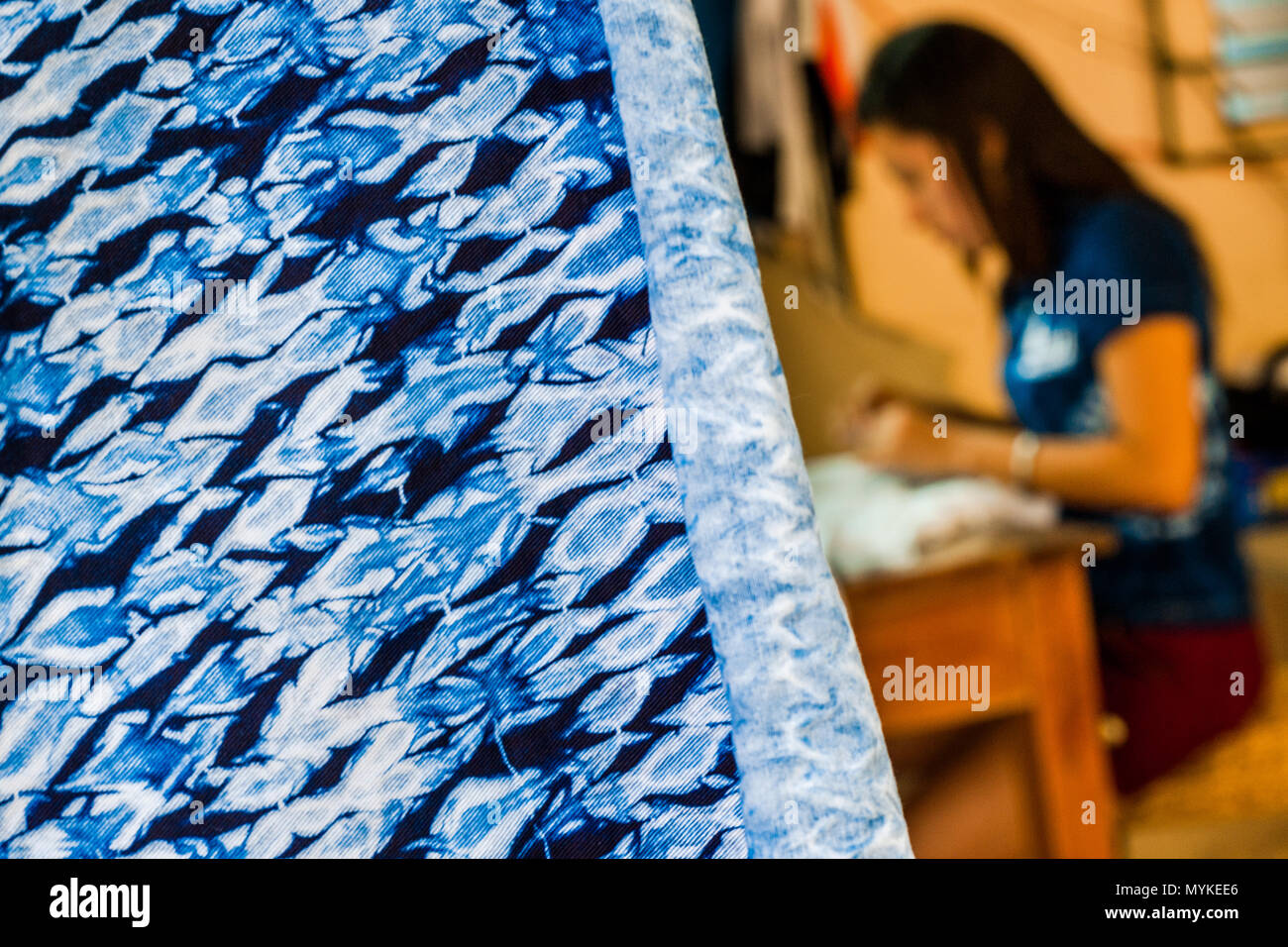 Ein indigo-gefärbten Stoff wird gesehen, vor einer Näherin arbeiten in einem Handwerklichen Kleidung Workshop in Santiago Nonualco, El Salvador aufgehängt. Stockfoto