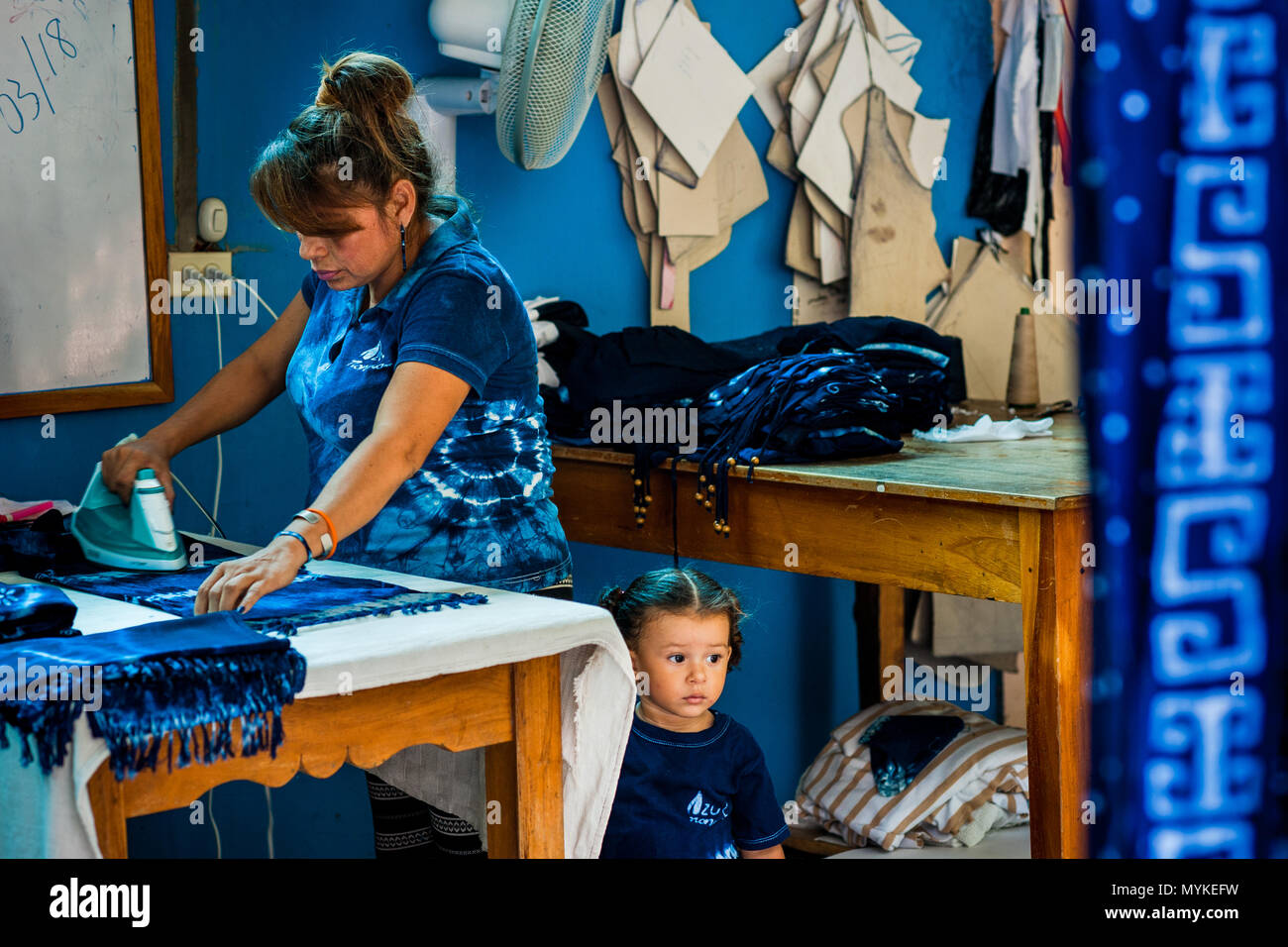 Eine salvadorianische Frau Eisen ein Indigo gefärbt Schal in einem Handwerklichen Kleidung Workshop in Santiago Nonualco, El Salvador. Stockfoto