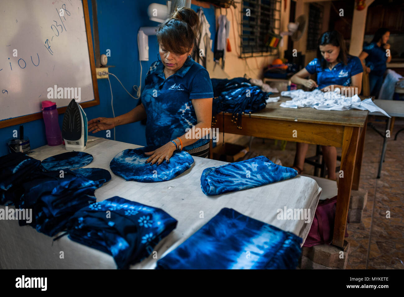 Eine salvadorianische Frau Eisen ein Indigo gefärbten Kissen in einem Handwerklichen Kleidung Workshop in Santiago Nonualco, El Salvador. Stockfoto