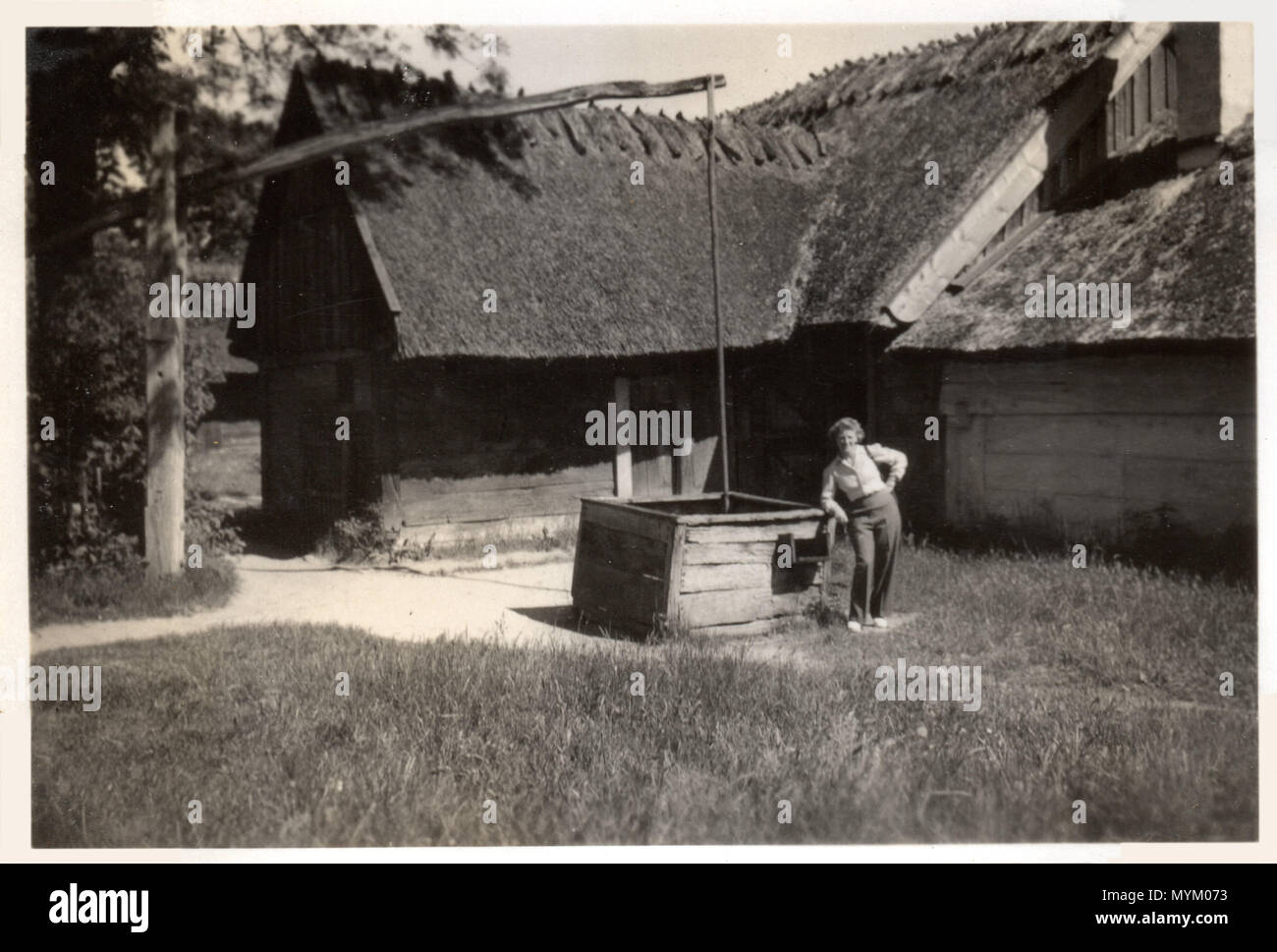 Frau stellt durch ein altes - Gegengewicht gut von einem reetgedeckten Bauernhaus in der Nähe von Odense auf der Insel Fünen in Dänemark. Foto gemacht ca. 1946 Stockfoto Frau stellt durch ein altes - Gegengewicht gut von einem reetgedeckten Bauernhaus in der Nähe von Odense auf der Insel Fünen in Dänemark. Foto gemacht ca. 1946 Stockfoto