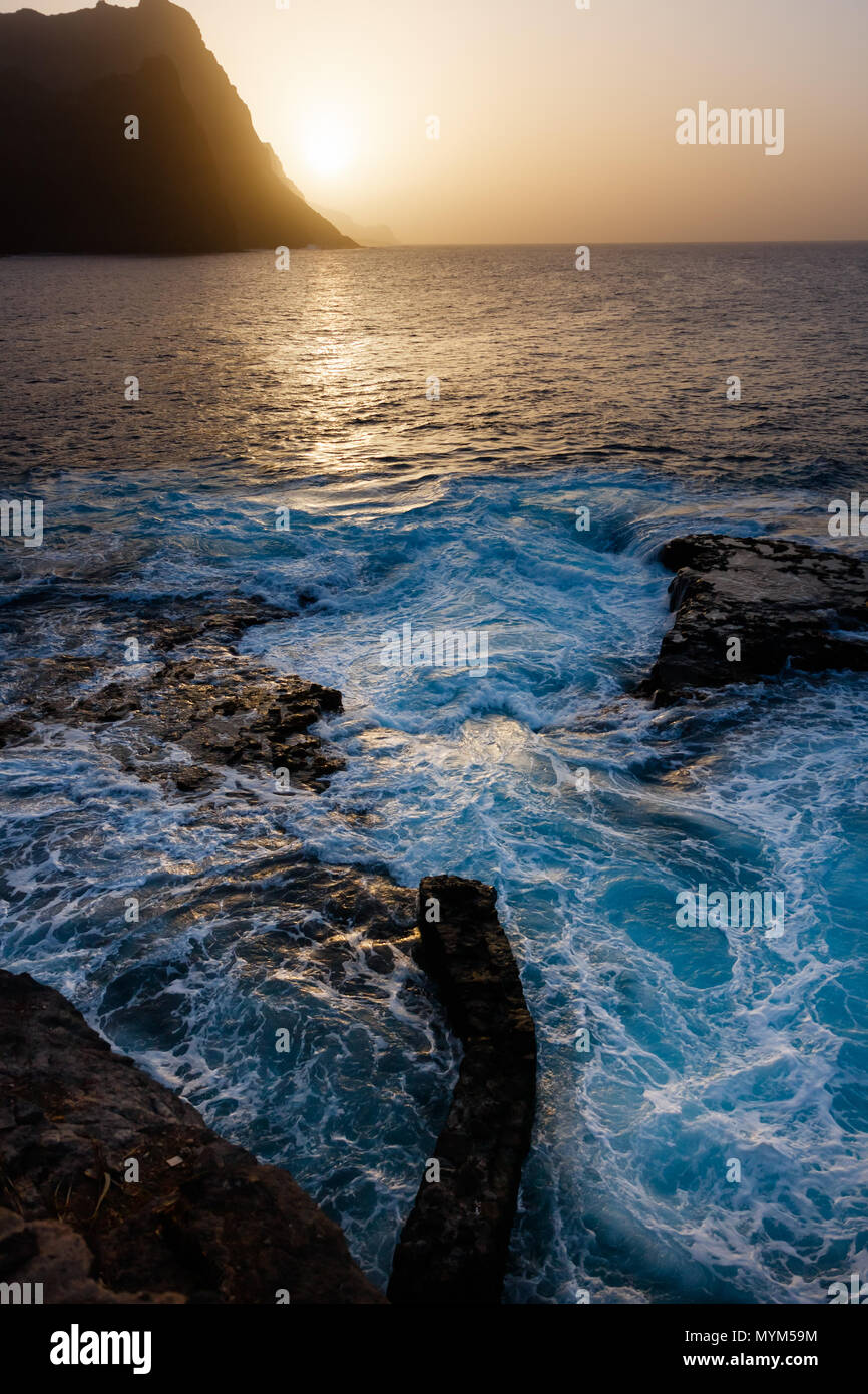 Staubige Sonnenuntergang und turbulenten Wellen am felsigen Strand von Santo Antao Insel Stockfoto