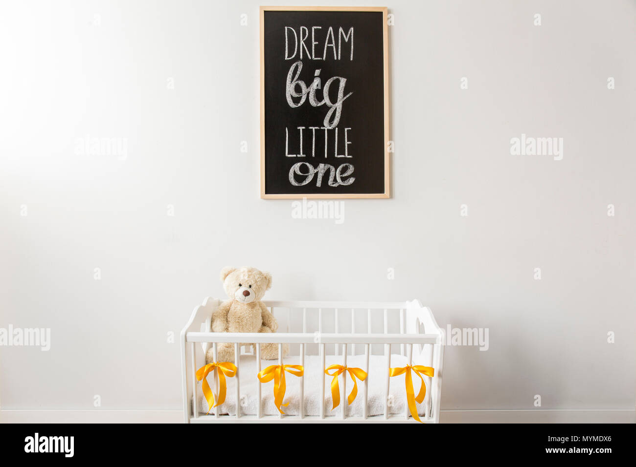 Aufnahme einer Krippe mit einem Teddybären und eine Tafel an der Wand in einem Kinderzimmer Stockfoto