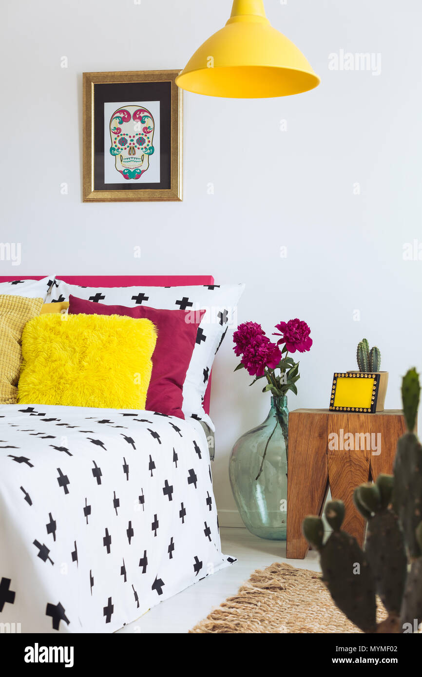 Schlafzimmer mit Federdecke, gelbe Lampe und Sugar Skull Poster Stockfoto