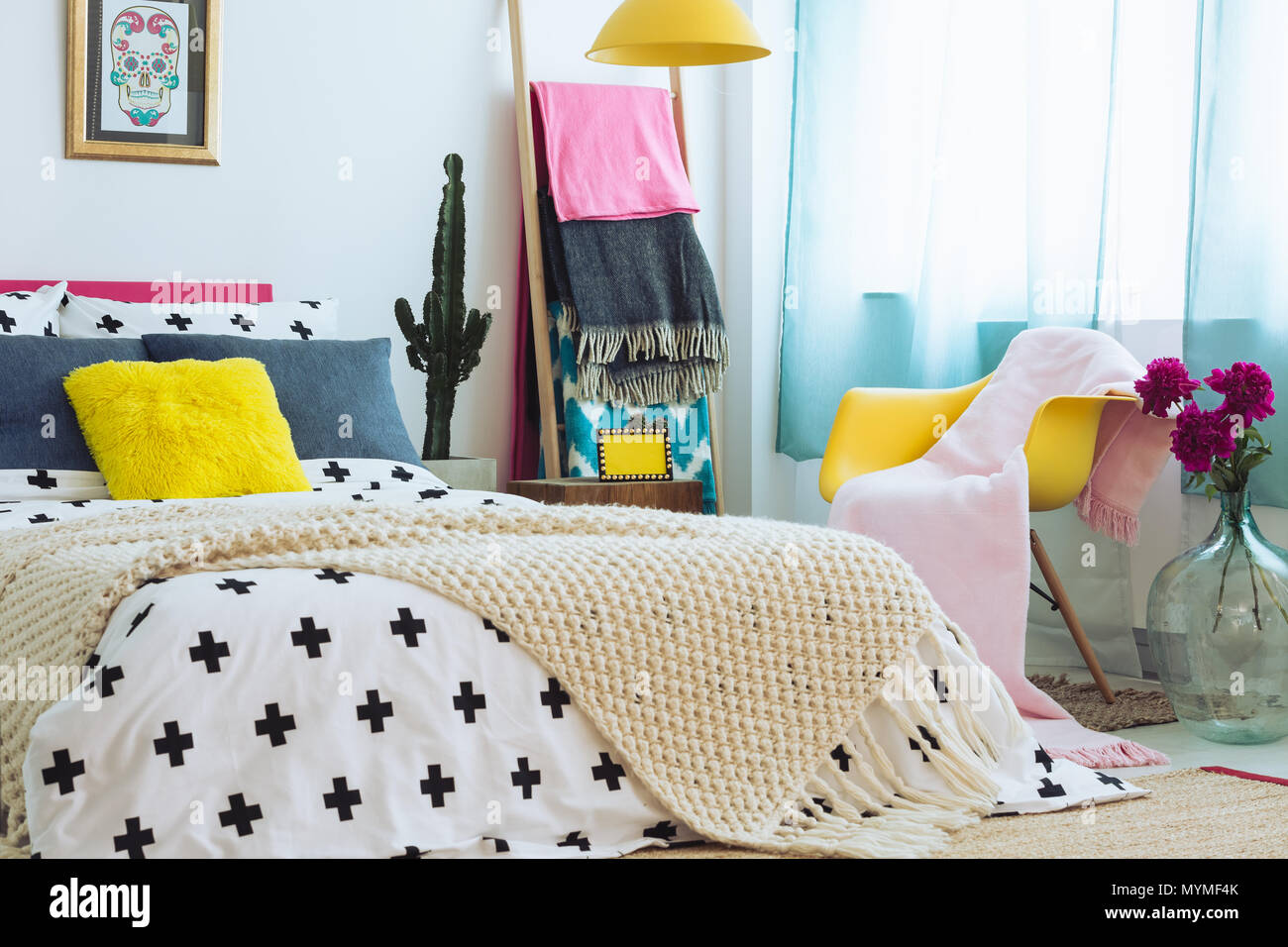 Trendy Schlafzimmer mit bunter Bettwäsche, Decken und Kombination von Materialien Stockfoto