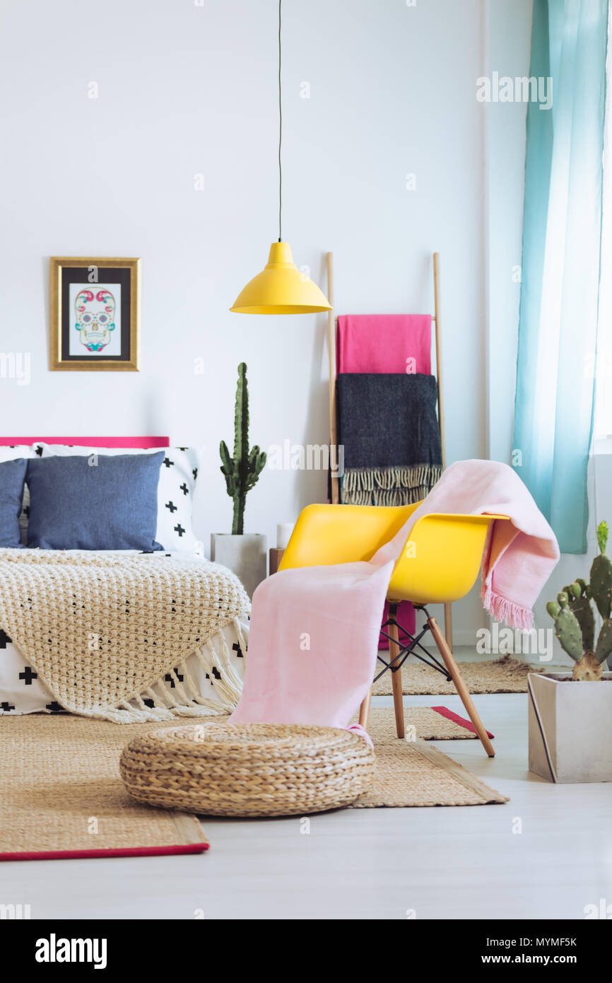 Stilvolle helles Schlafzimmer mit gelben Lampe, einem Sessel und Schädel Poster Stockfoto