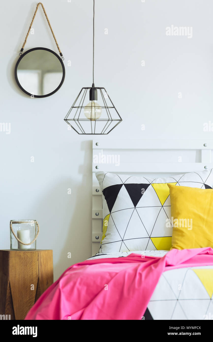 Weiße geometrische Schlafzimmer mit industriellen Lampe, triangle Quilt, runden Spiegel Stockfoto