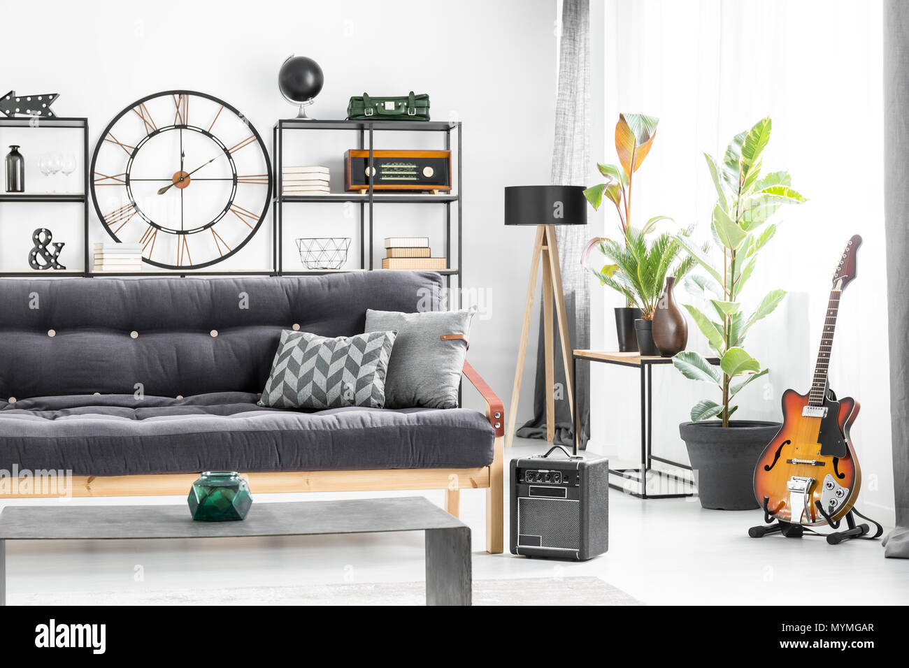 Grau Kissen Auf Dunklen Sofa Vor Eine Tabelle In Der Man Wohnzimmer Interieur Mit Gitarre Und Designer Uhr An Der Wand Stockfotografie Alamy