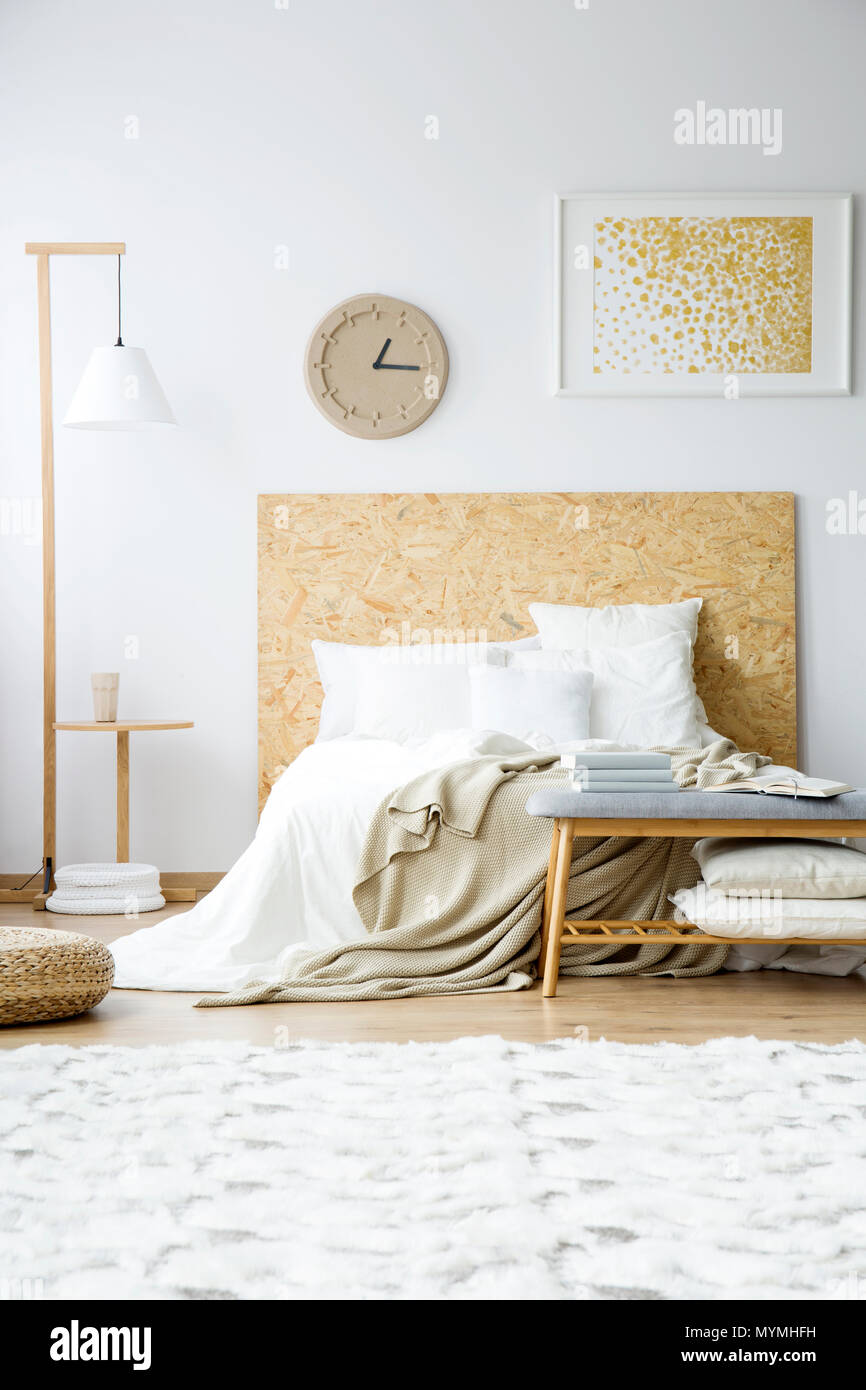 Papier und Gemälde an der Wand über dem Bett neben einem hölzernen Lampe in  natürlichen Schlafzimmer mit Teppich Stockfotografie - Alamy