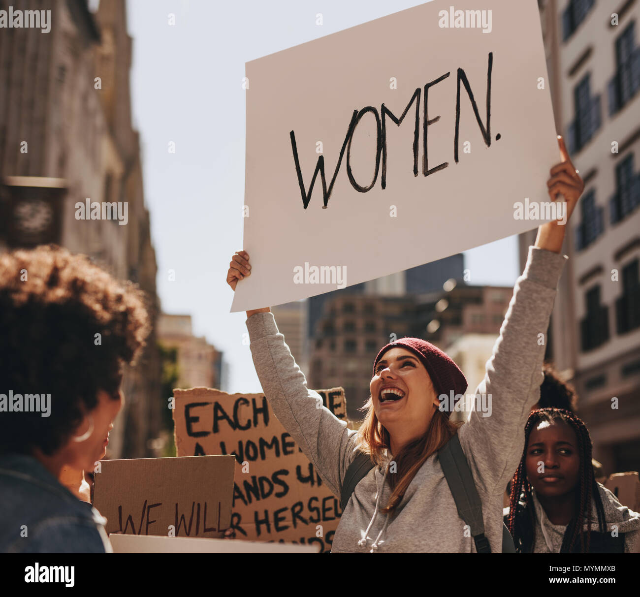 Glückliche junge Frau Hand schriftliche Protest an der Frau März. Gruppe von Frauen demonstrieren im Freien. Stockfoto