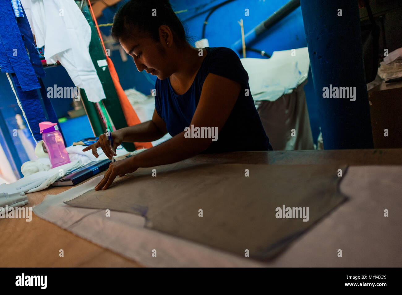 Eine salvadorianische Näherin schöpft aus einem Stoff, mit der natürlichen blue Indigo gefärbt, danach in einem Kleidung Workshop in Santiago Nonualco, El Salvador. Stockfoto