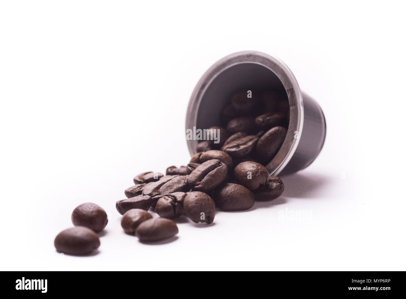 Geröstete Kaffeebohnen spill Aus einer Kapsel auf weißem Hintergrund Stockfoto