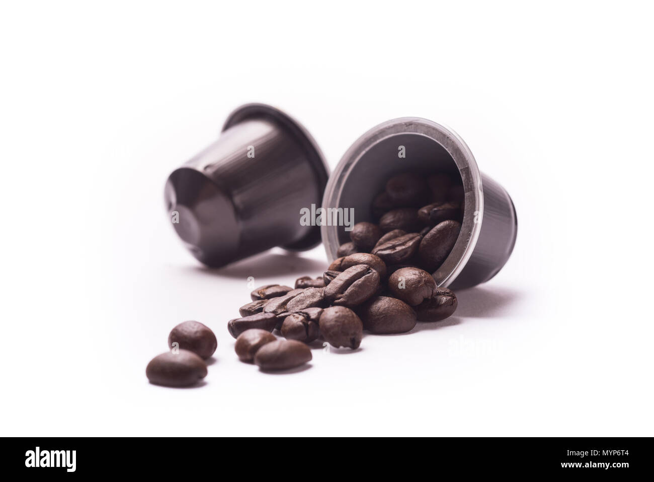 Geröstete Kaffeebohnen spill Aus einer Kapsel auf weißem Hintergrund Stockfoto