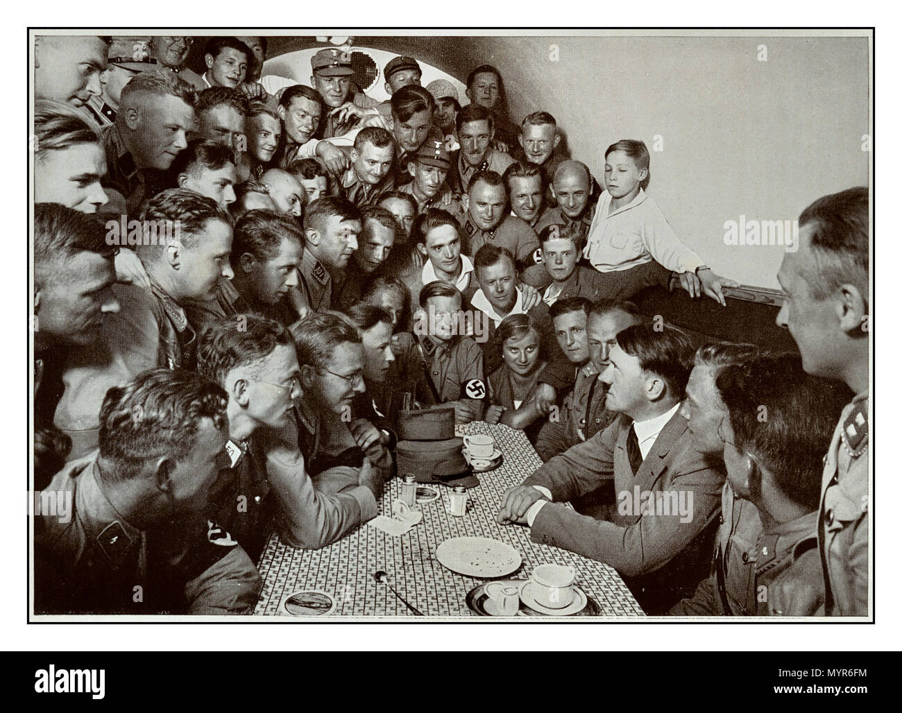Adolf Hitler aus den 1930er Jahren spricht mit einer Gruppe junger engagierter Anhänger in der Kellerkantine des Münchner Braunhauses, einem Hostel für junge Männer der Nazi-SA in München Stockfoto