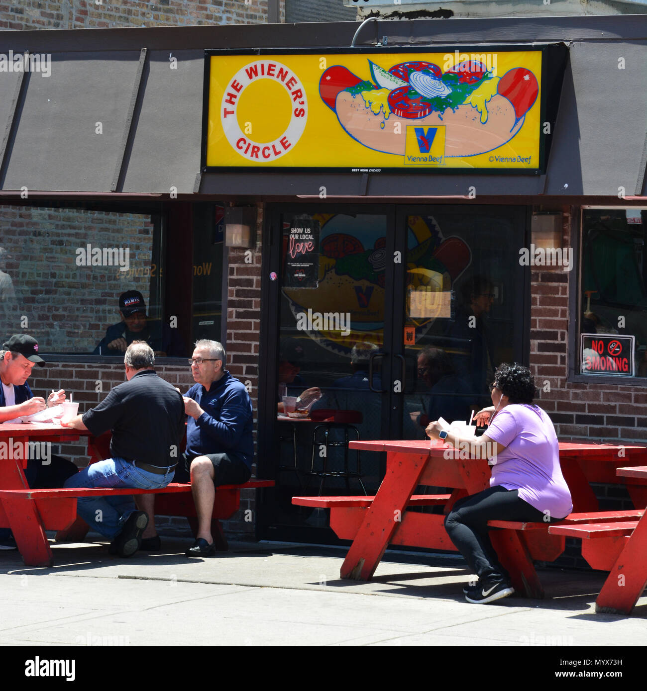 Die Menschen genießen Chicago Stil Hotdogs am Bürgersteig Picknicktische außerhalb des Wieners Kreis, wo Sie berühmt für dishing Beleidigungen mit dem Essen sind. Stockfoto