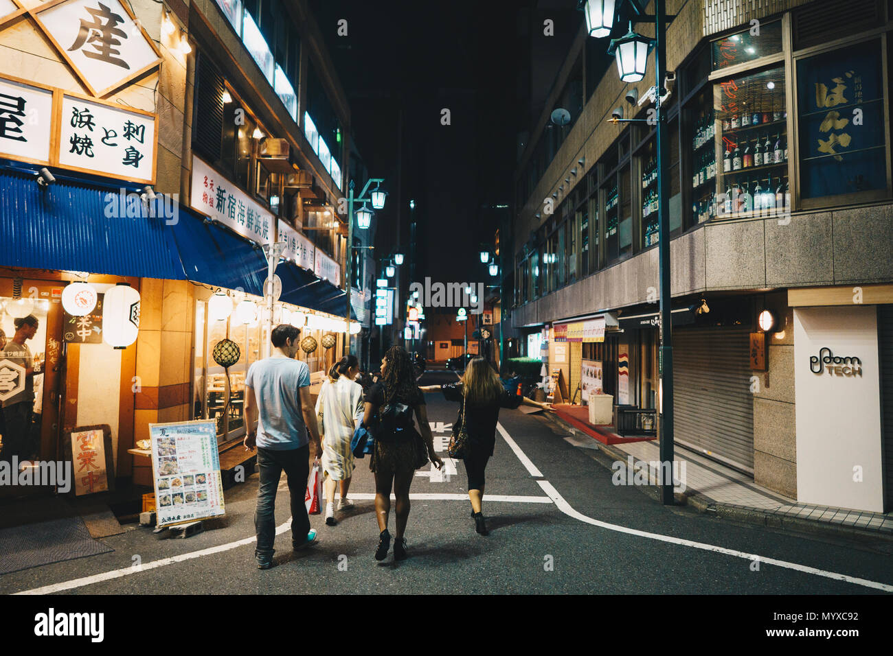 Eine Gruppe von Freunden zu Fuß durch Tokio bei Nacht Stockfoto