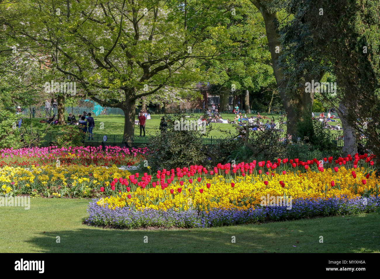 Bunte Blumenbeete in einem britischen Park mit Menschen entspannend auf einem suuny Tag. Stockfoto
