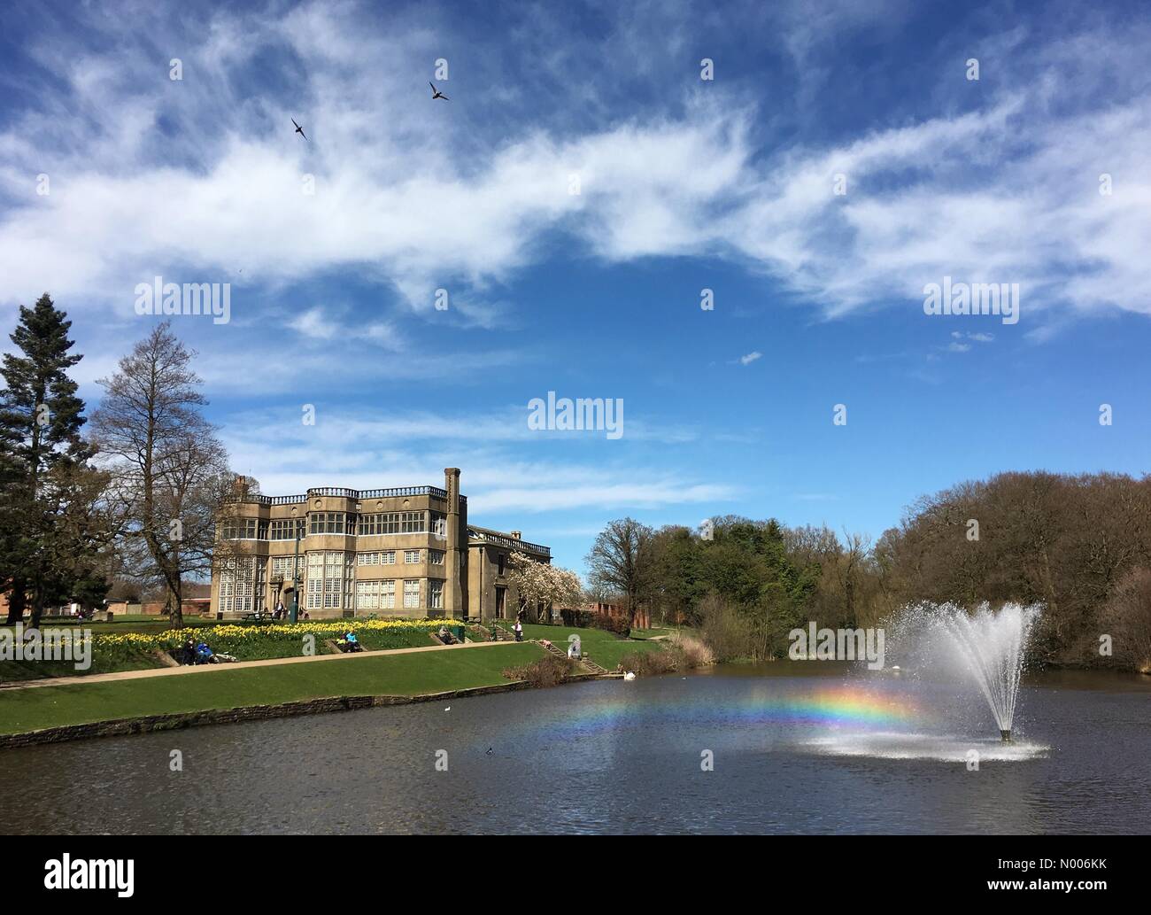 UK-Wetter sonnigen Sonntagnachmittag Astley Park in Chorley, Lancashire. Regenbogen gegossen von Brunnen vor Astley Hall Stockfoto